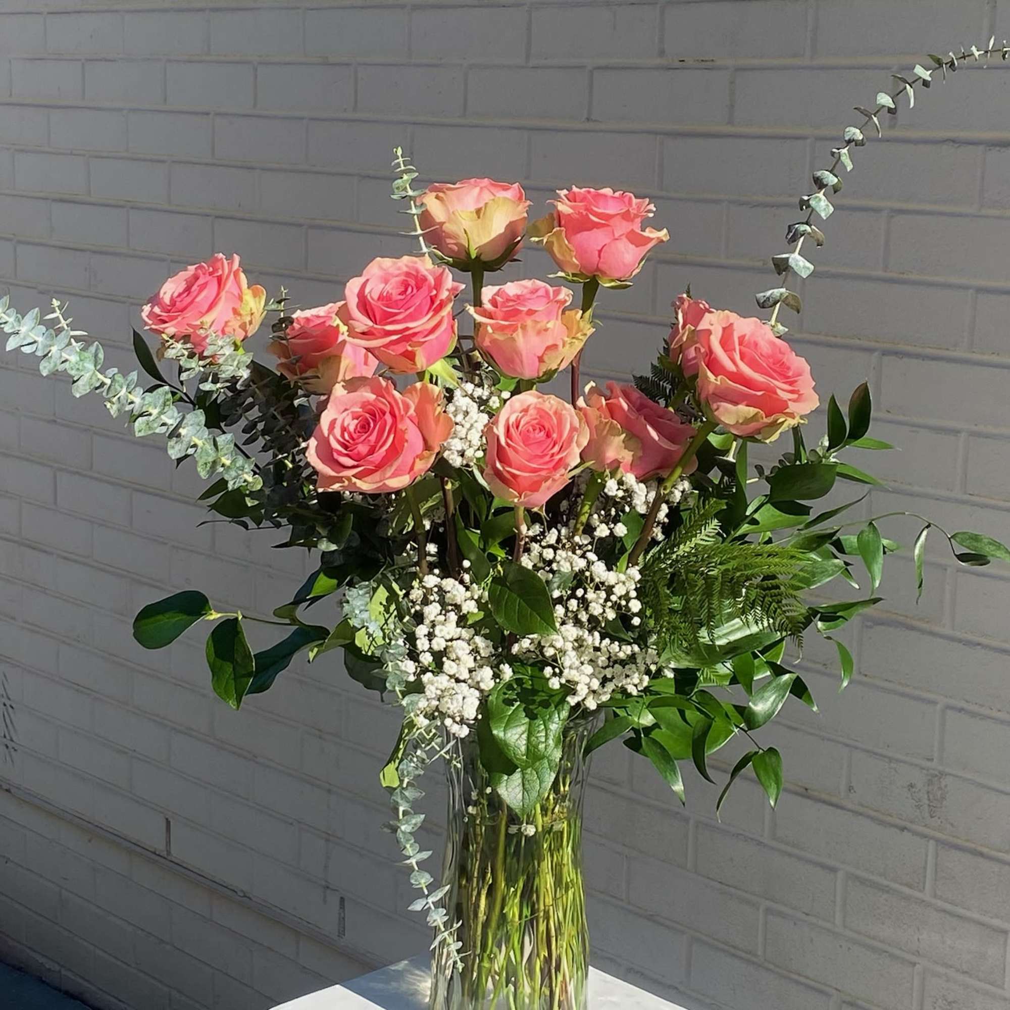 Pink roses in a clear glass vase with white filler flowers