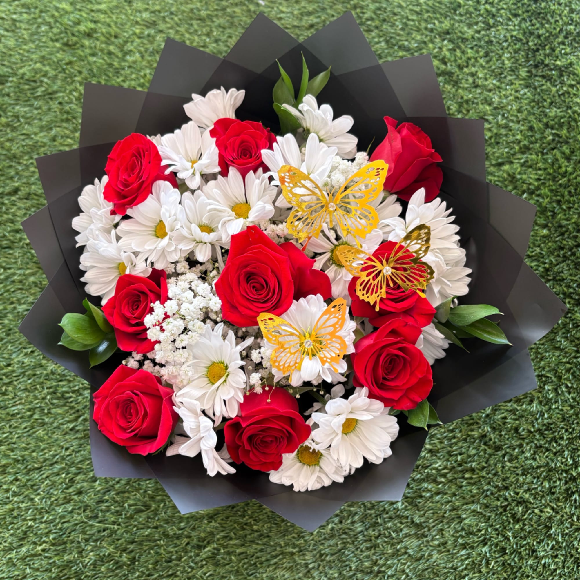Bouquet of red roses and white daisies with butterfly decorations