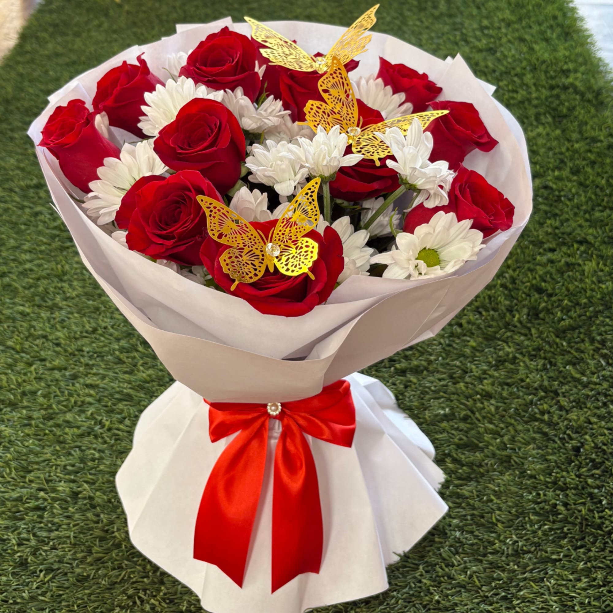 Bouquet of red roses and white daisies wrapped in white paper