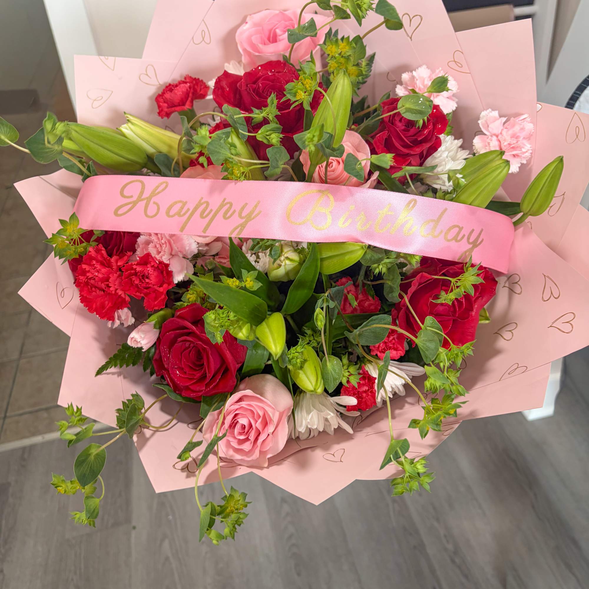 Pink and red bouquet with roses, lilies, and carnations wrapped in pink paper