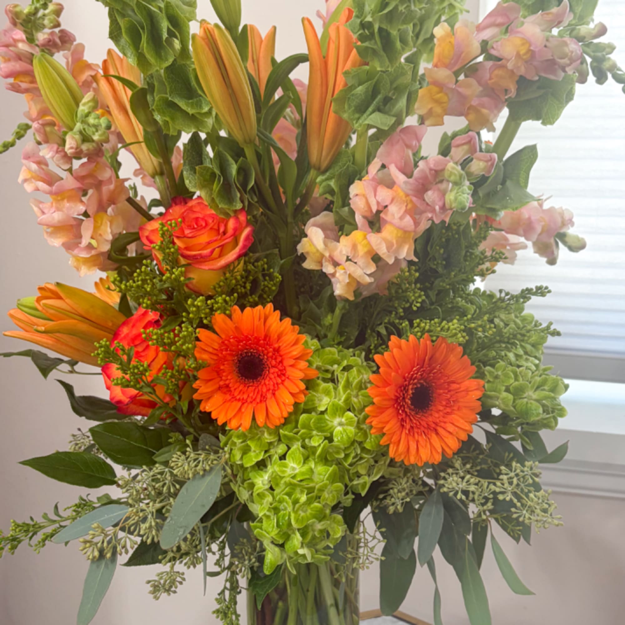 Tall bouquet with orange lilies, gerbera daisies, roses, and pink snapdragons