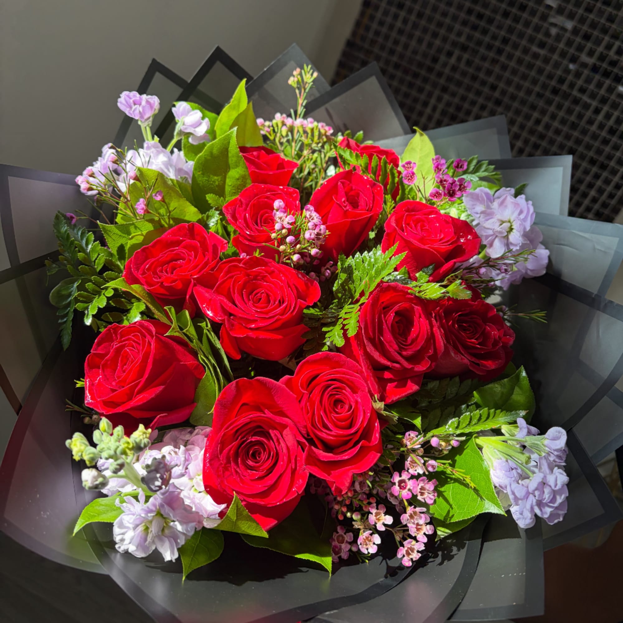Bouquet of red roses with pale purple flowers and black wrap
