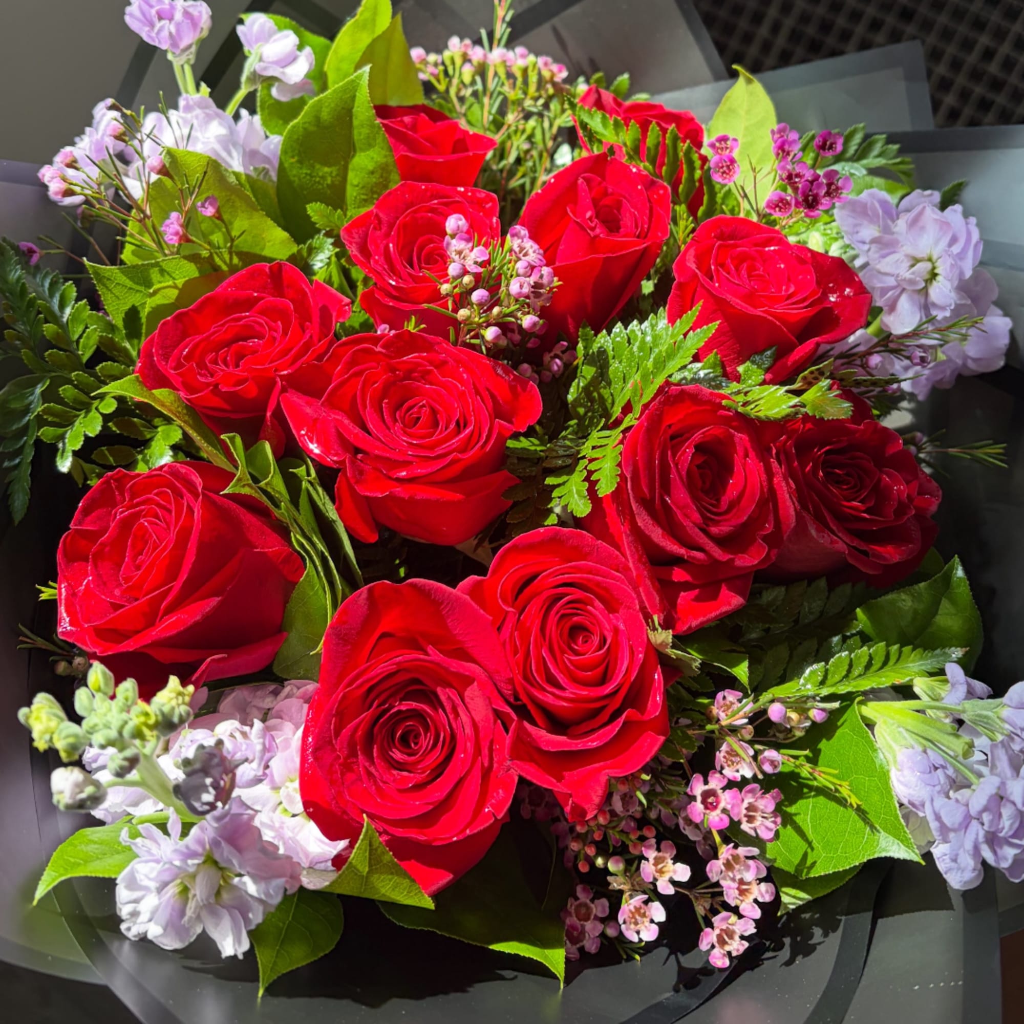 Bouquet of red roses with pale lavender flowers and greenery