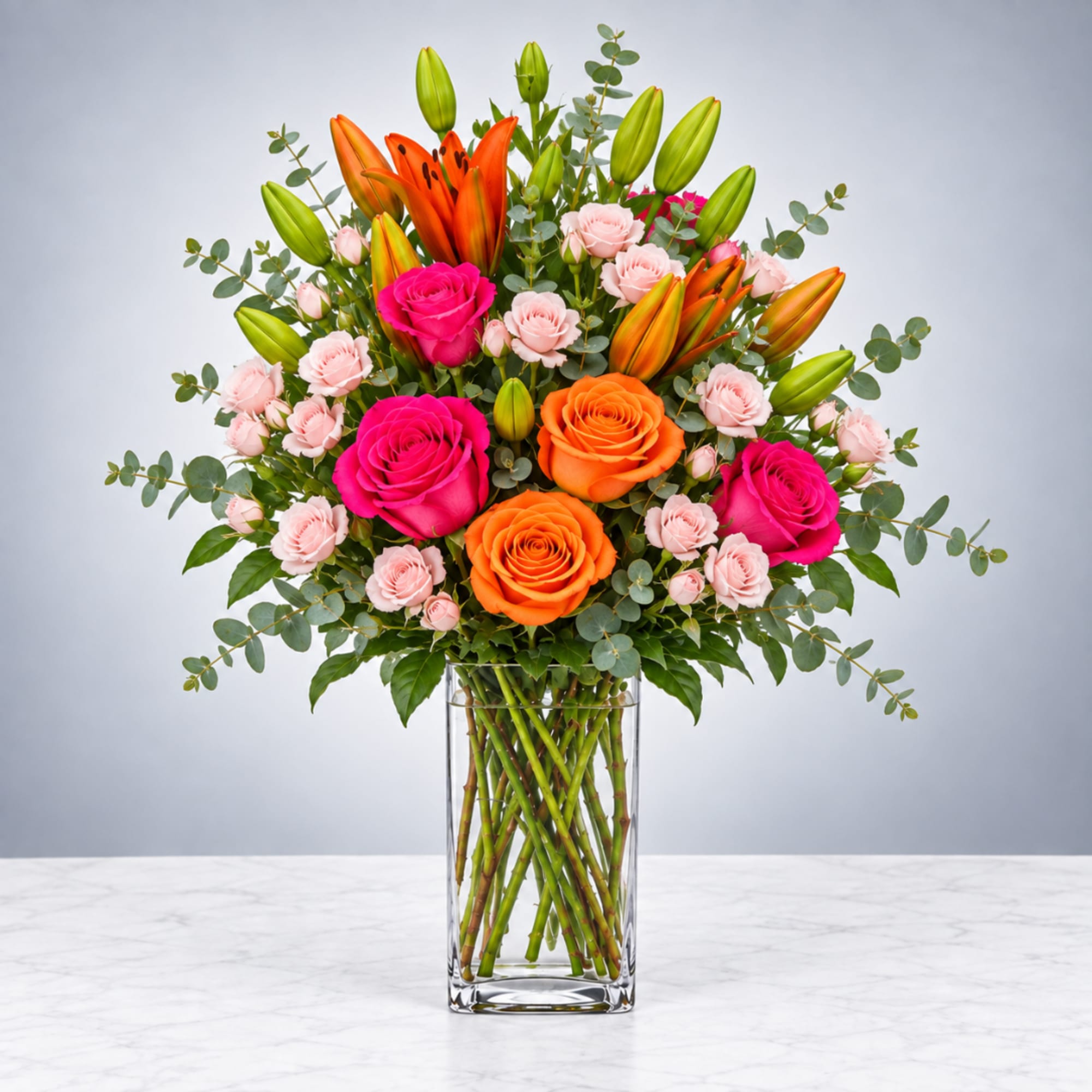 Bright mixed bouquet of roses and lilies in a clear glass vase