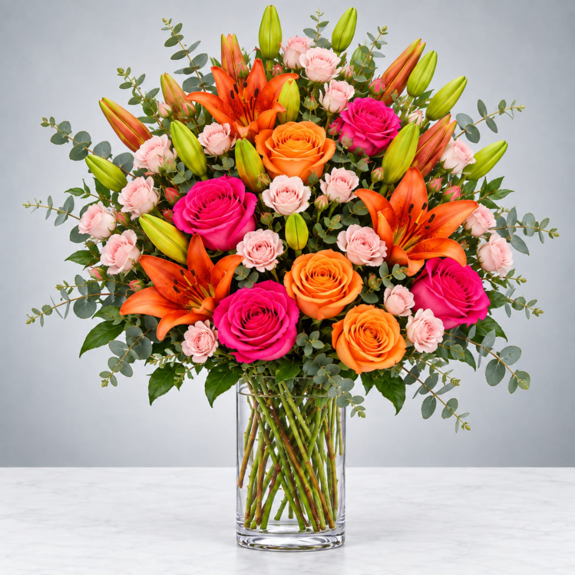 Bouquet of orange lilies, roses, and pink spray roses in a clear glass vase
