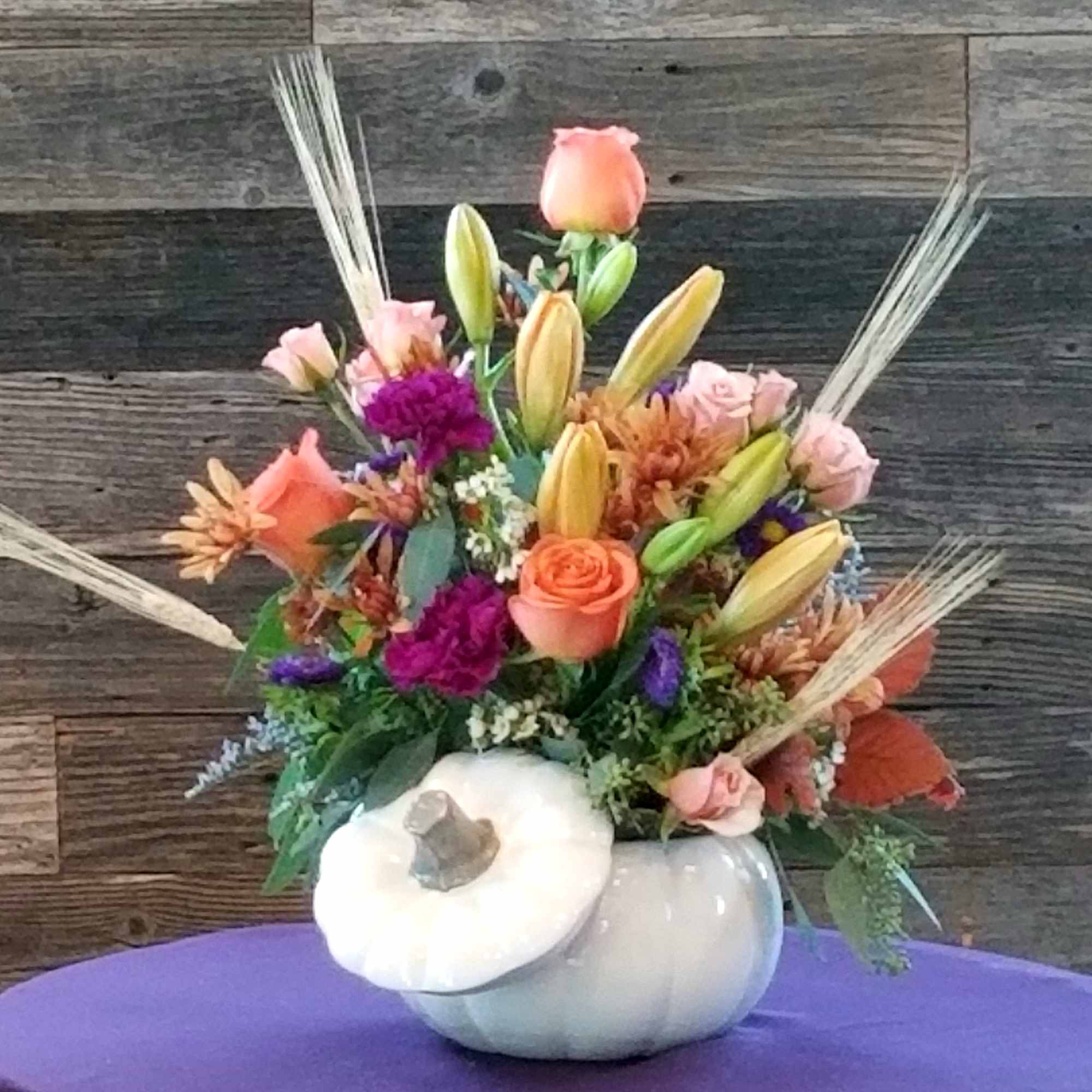 Autumn floral arrangement in a white pumpkin container with peach and pink blooms