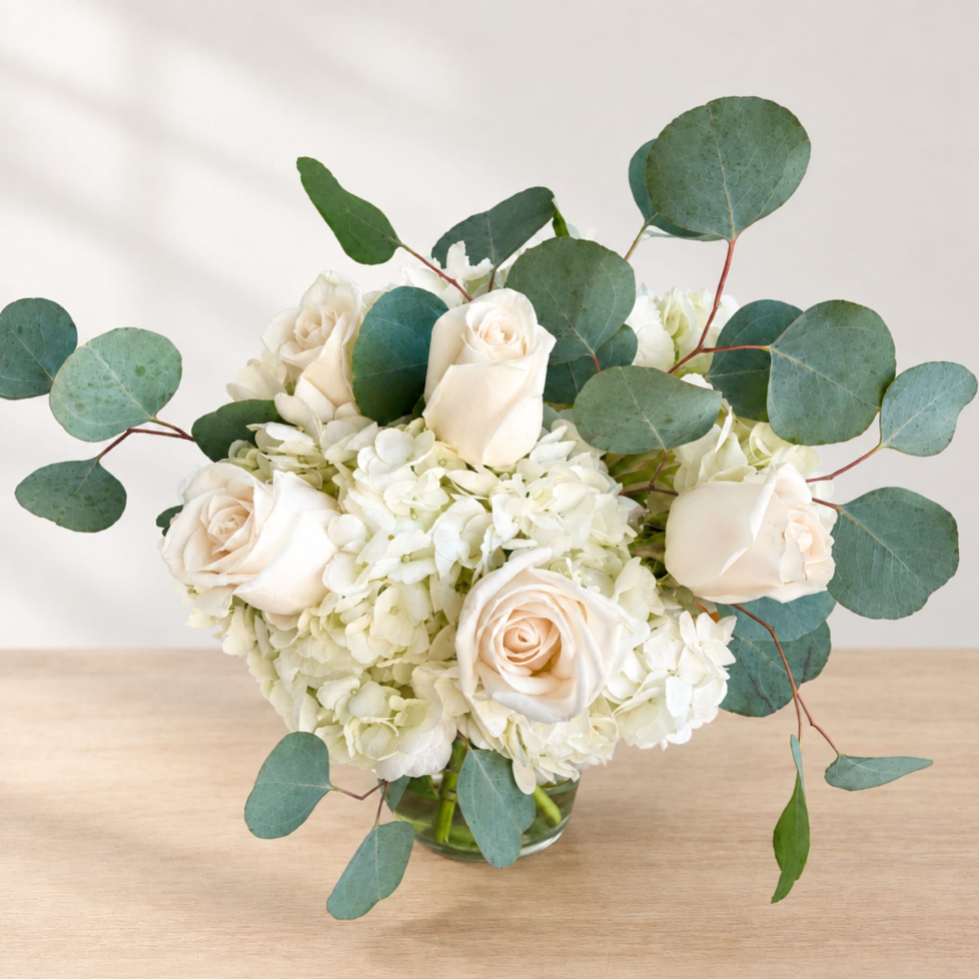 White roses and hydrangeas in a glass vase with eucalyptus, photo 2 of 2
