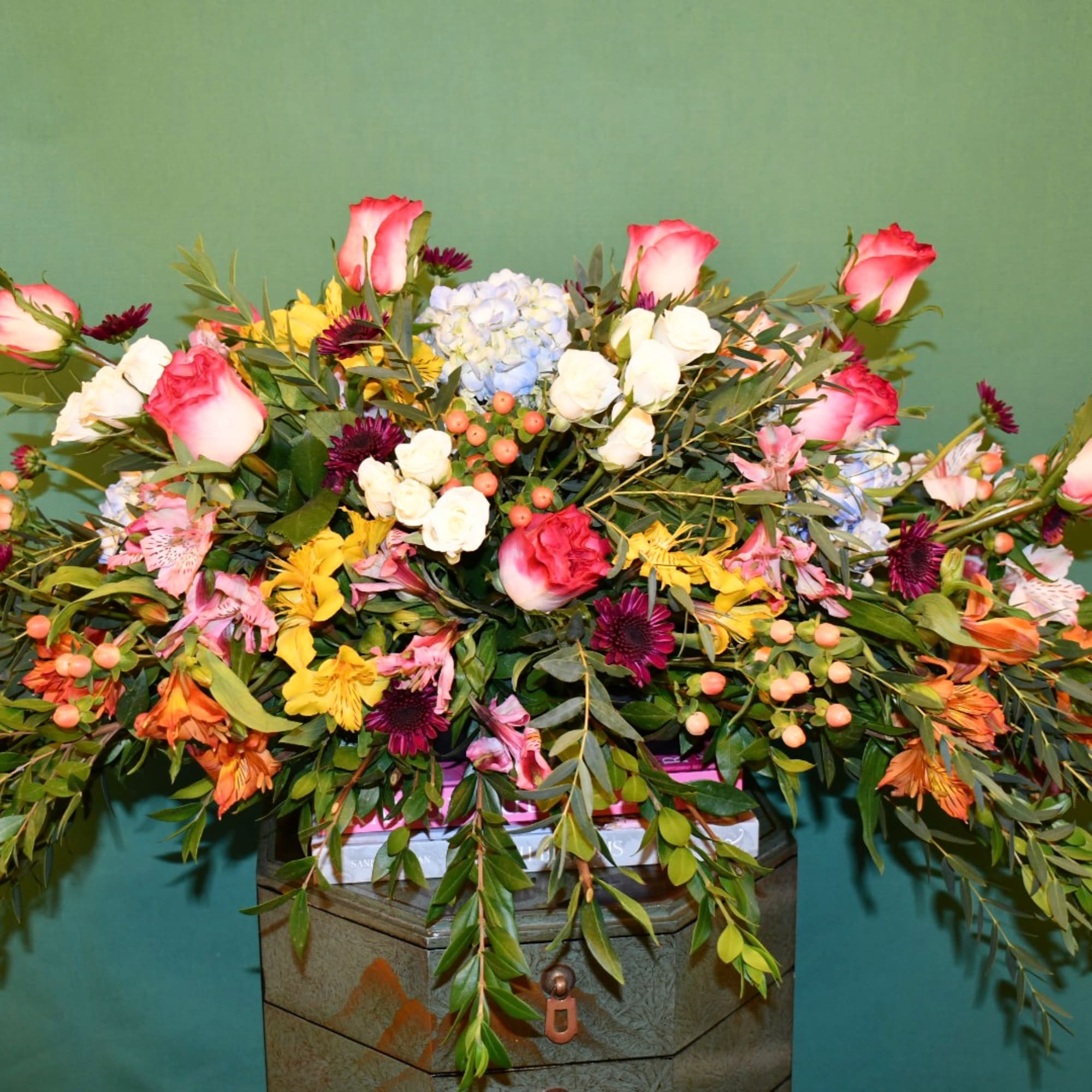 Large mixed flower arrangement with pink roses, hydrangea, and berries in a container