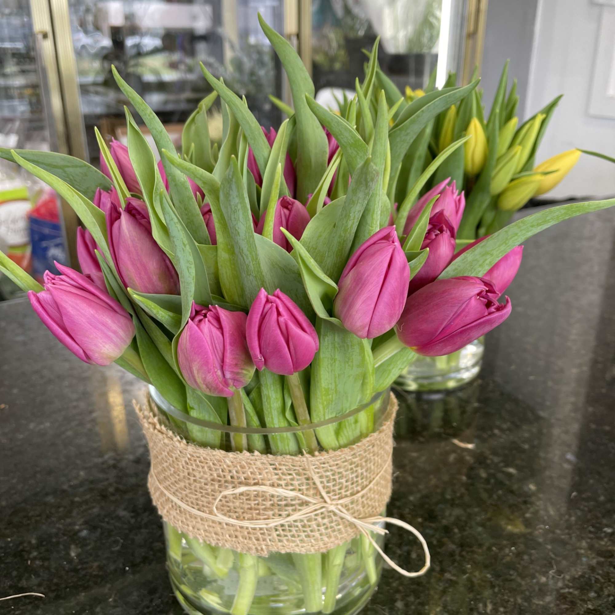 Pink tulips in a glass vase wrapped with burlap ribbon