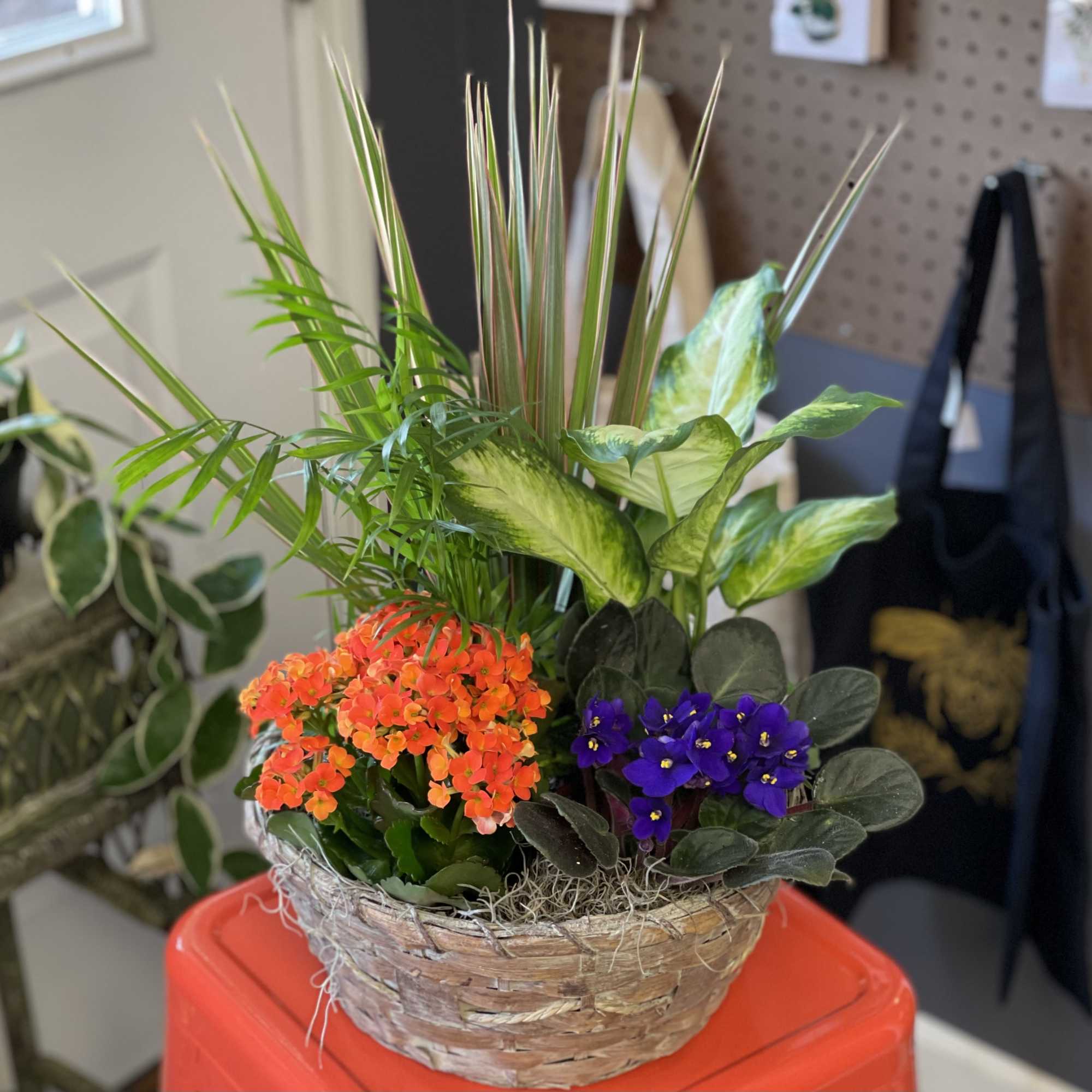 Basket planter with orange and purple flowers and tall tropical foliage