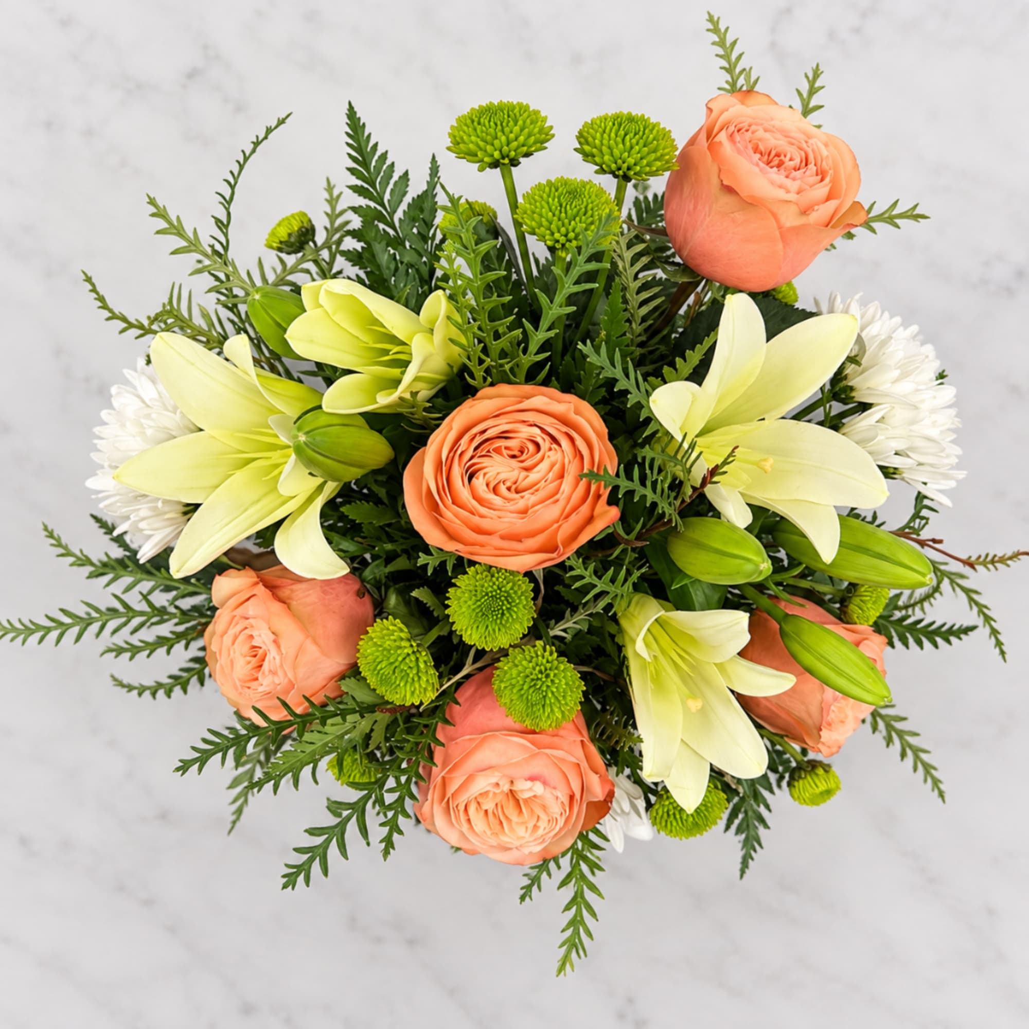 Peach roses and pale lilies in a compact bouquet