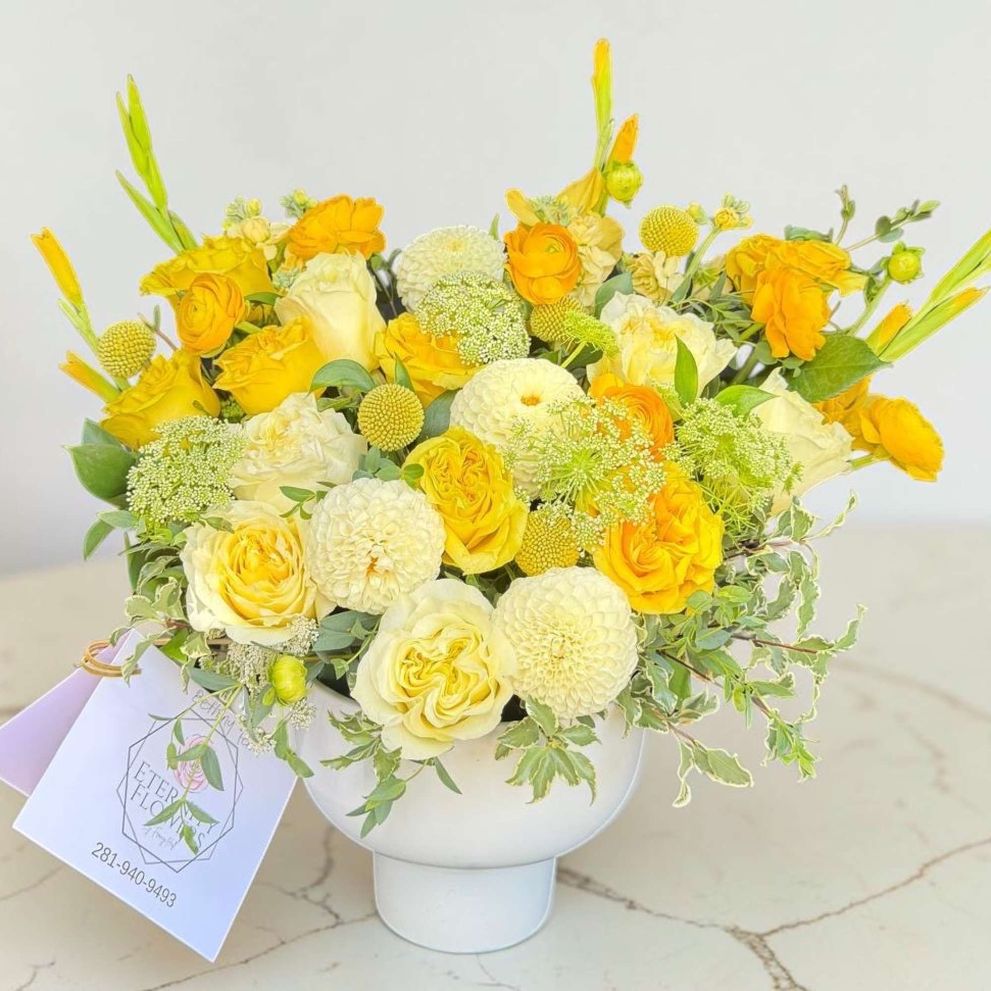 Yellow and white floral arrangement in a white vase