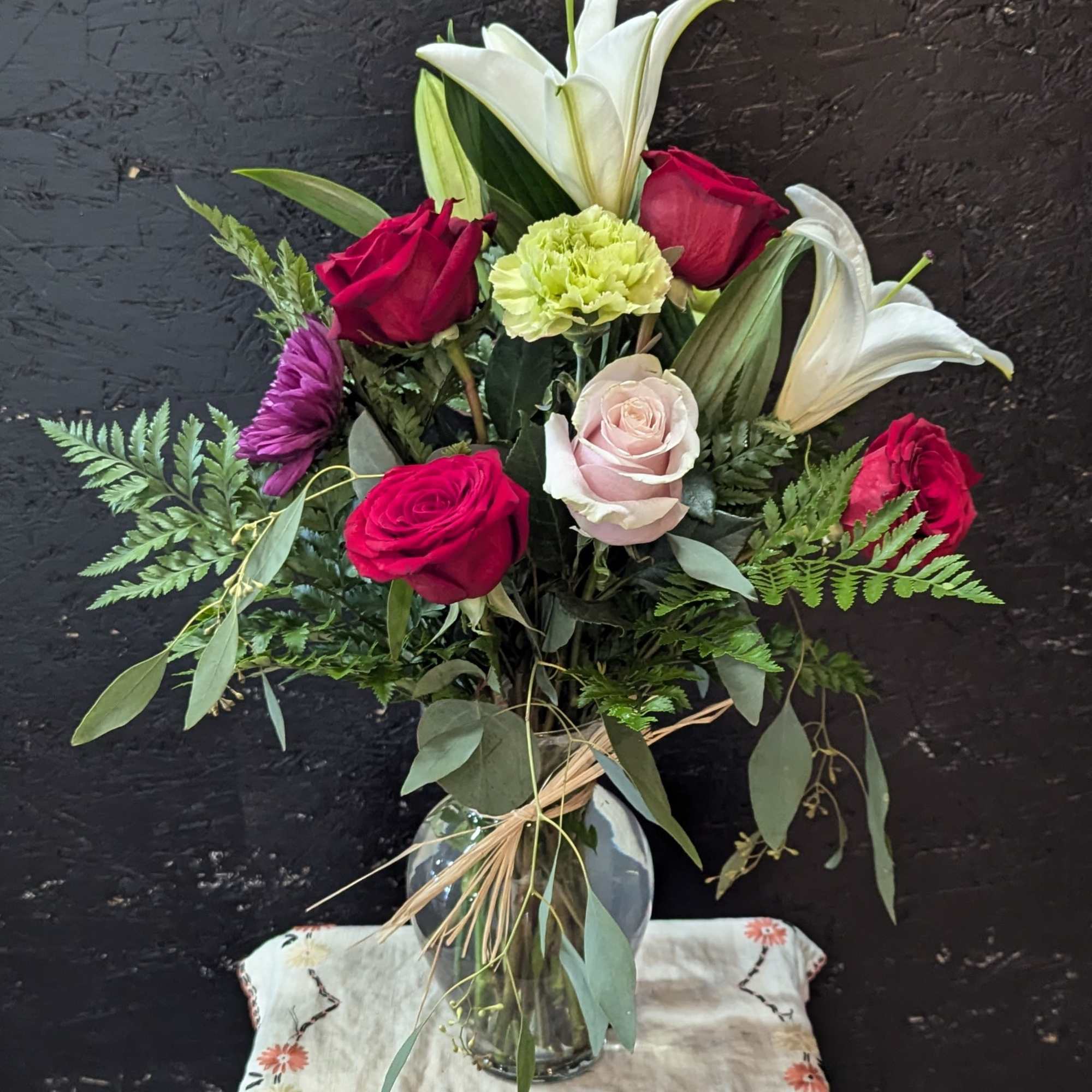 ORIENTAL LILIES, COLORFUL ASSORTMENT OF ROSES, MUMS CARNATIONS, EUCALYPTUS AND GREENS.