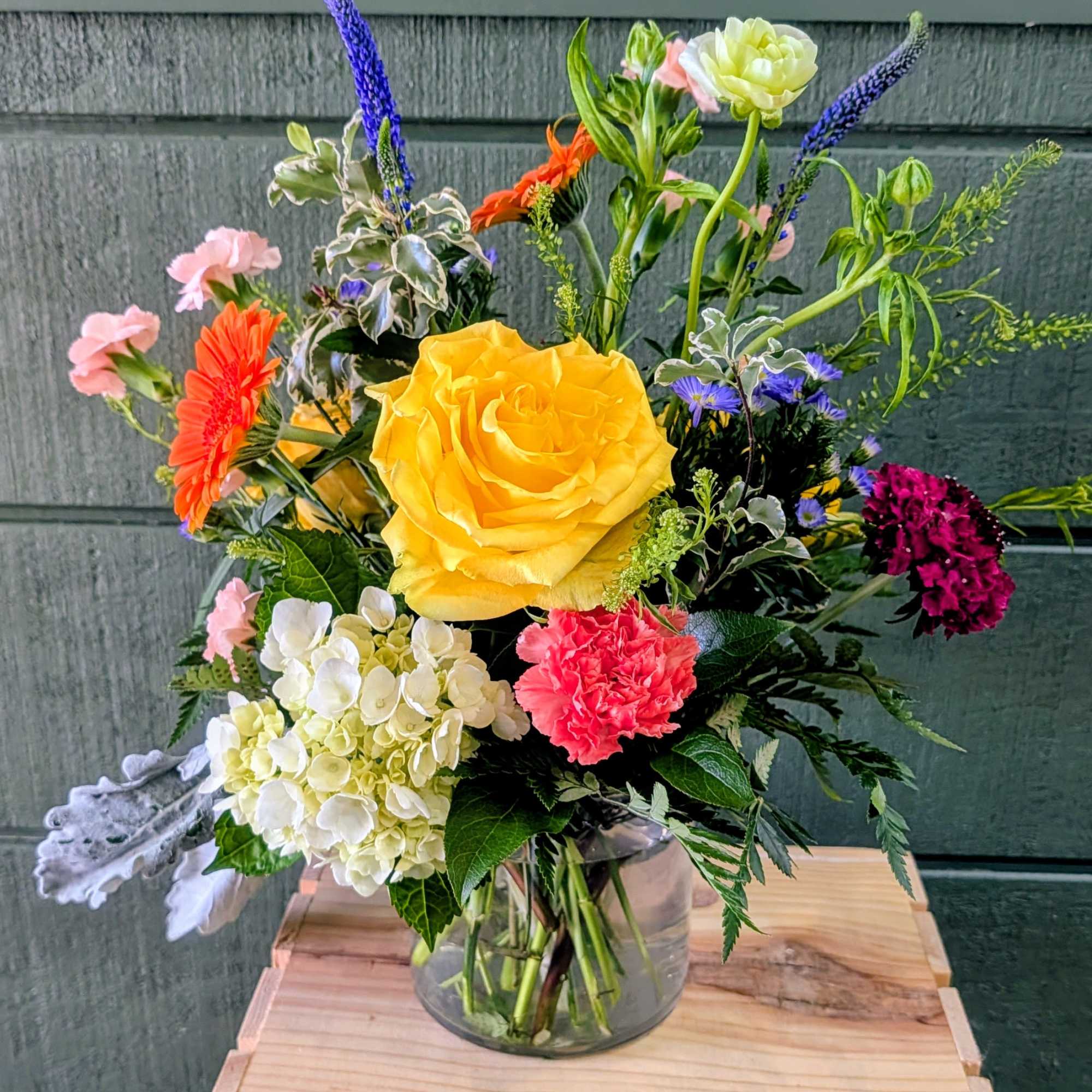 GLASS CONTAINER INCLUDES HYDRANGEA, ROSES, VERONICA, GERBERA DAISIES, MINI CARNATIONS, DUSTY MILLER