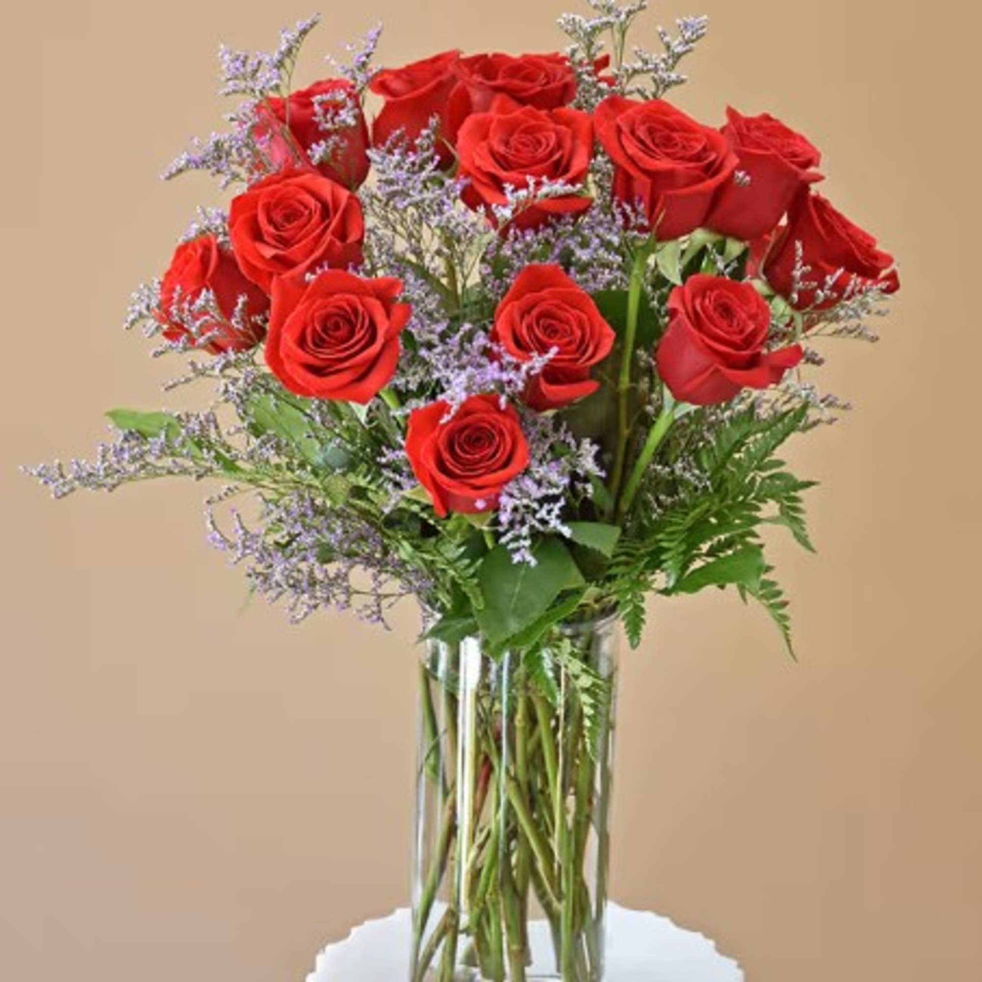Red roses arranged in a clear glass vase with purple filler flowers