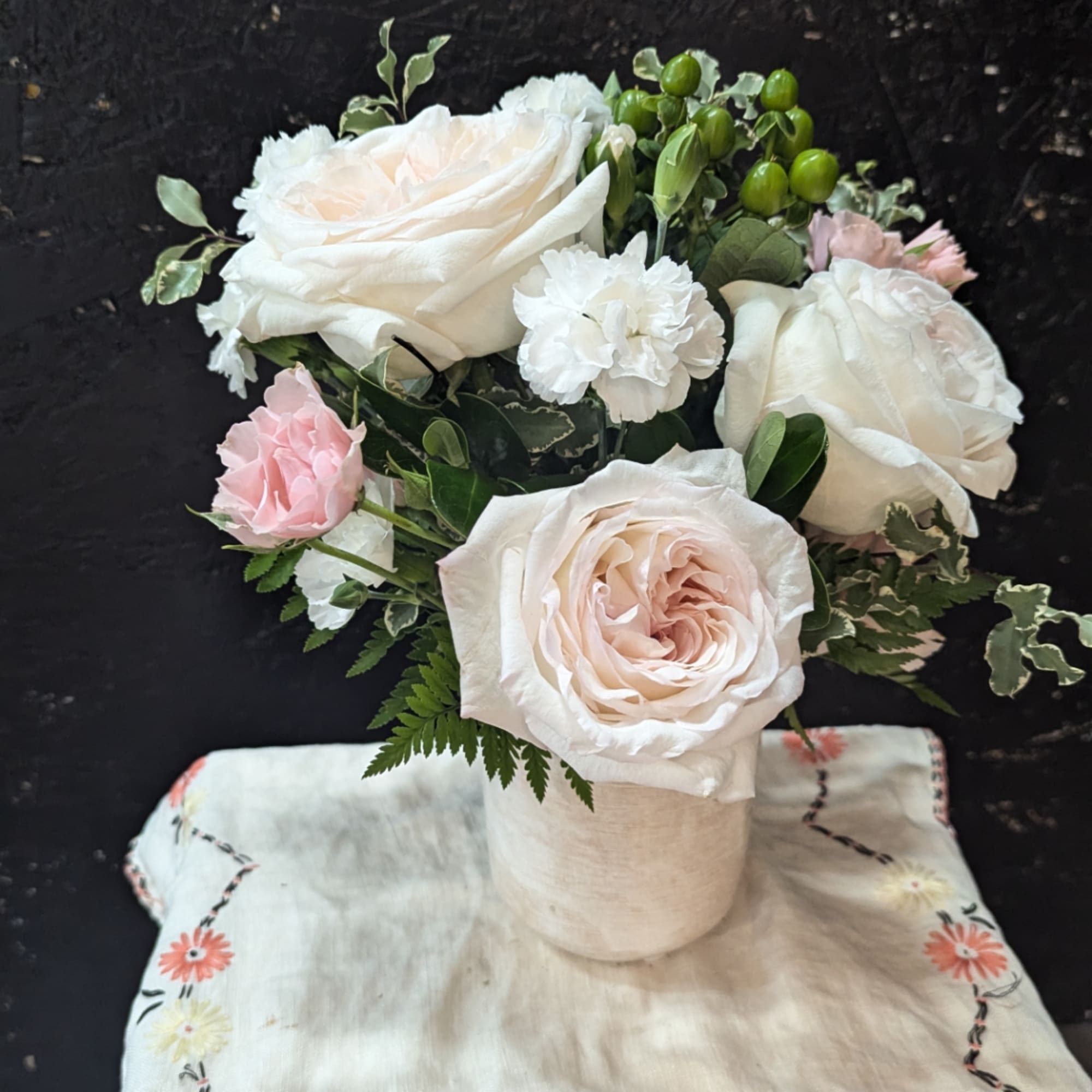 White and blush roses with white carnations in a vase