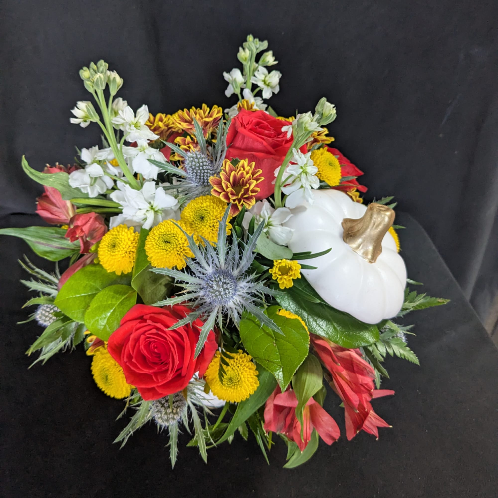 Mixed bouquet with red roses, yellow mums, white flowers, and a white pumpkin accent