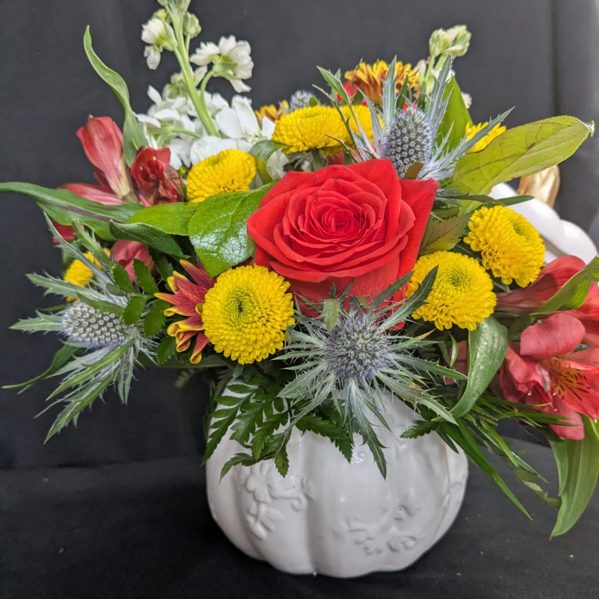 Red rose and yellow chrysanthemum bouquet in a white pumpkin vase