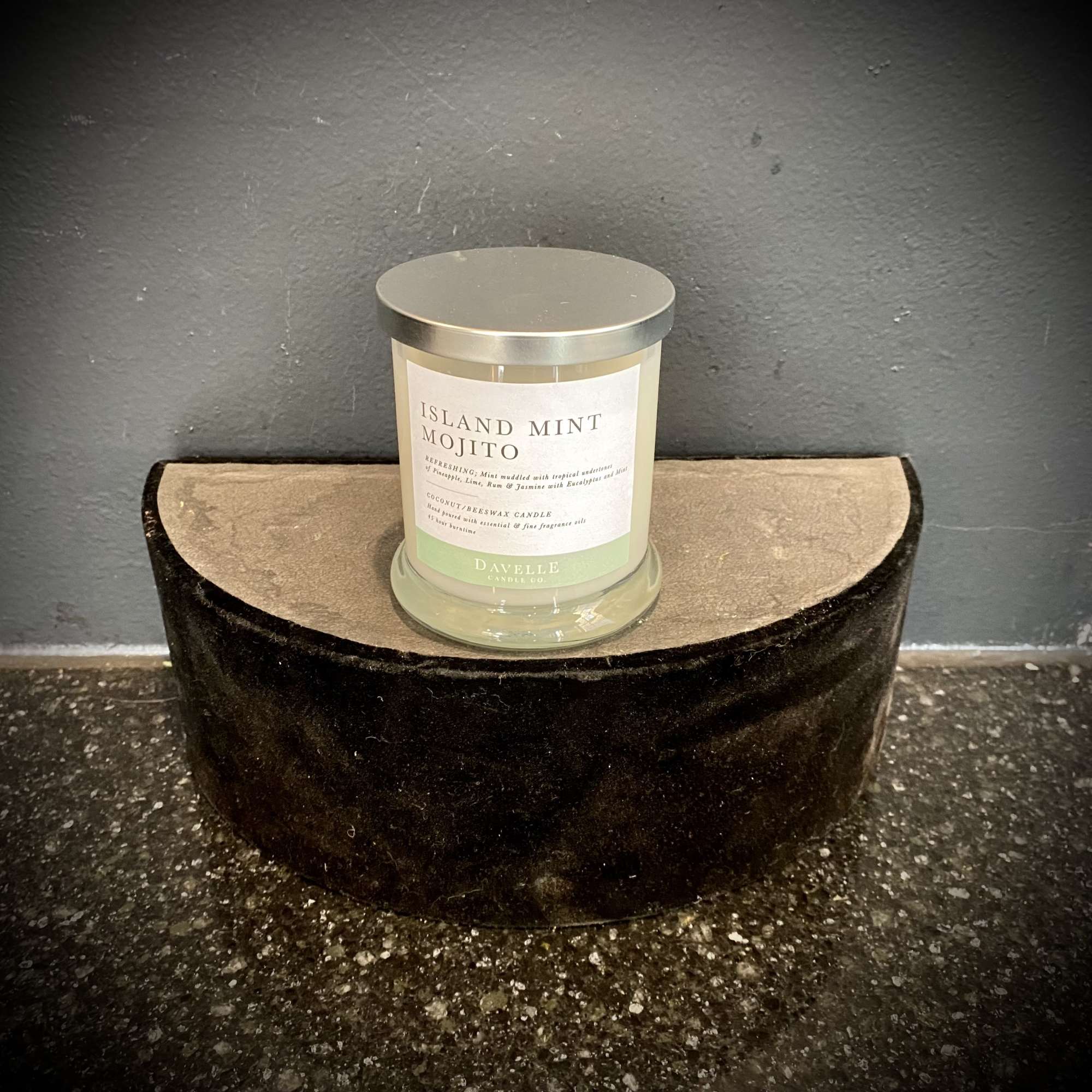 A mint-scented candle in a glass jar sits on a small decorative stand.