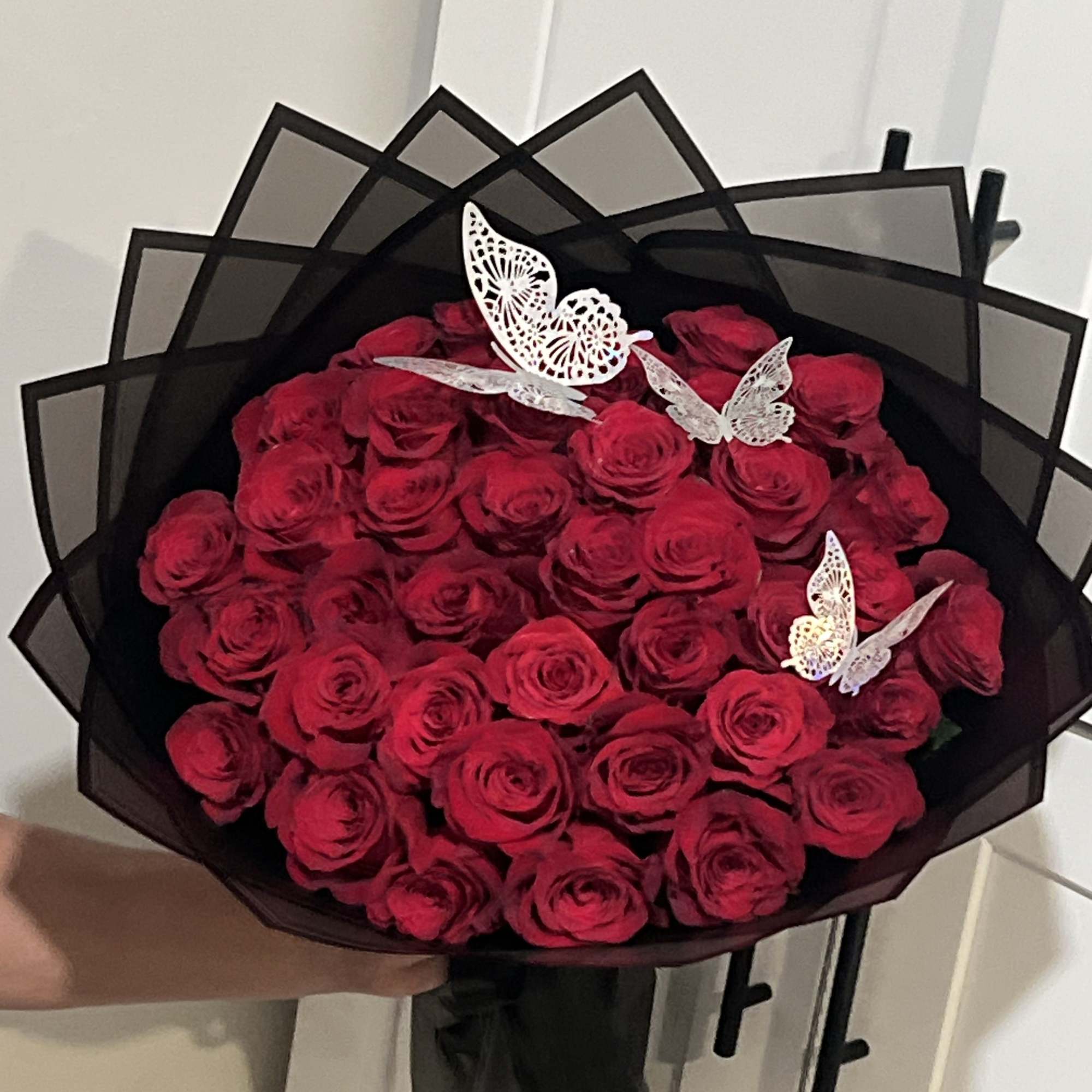 Bouquet of red roses wrapped in black paper with butterfly accents