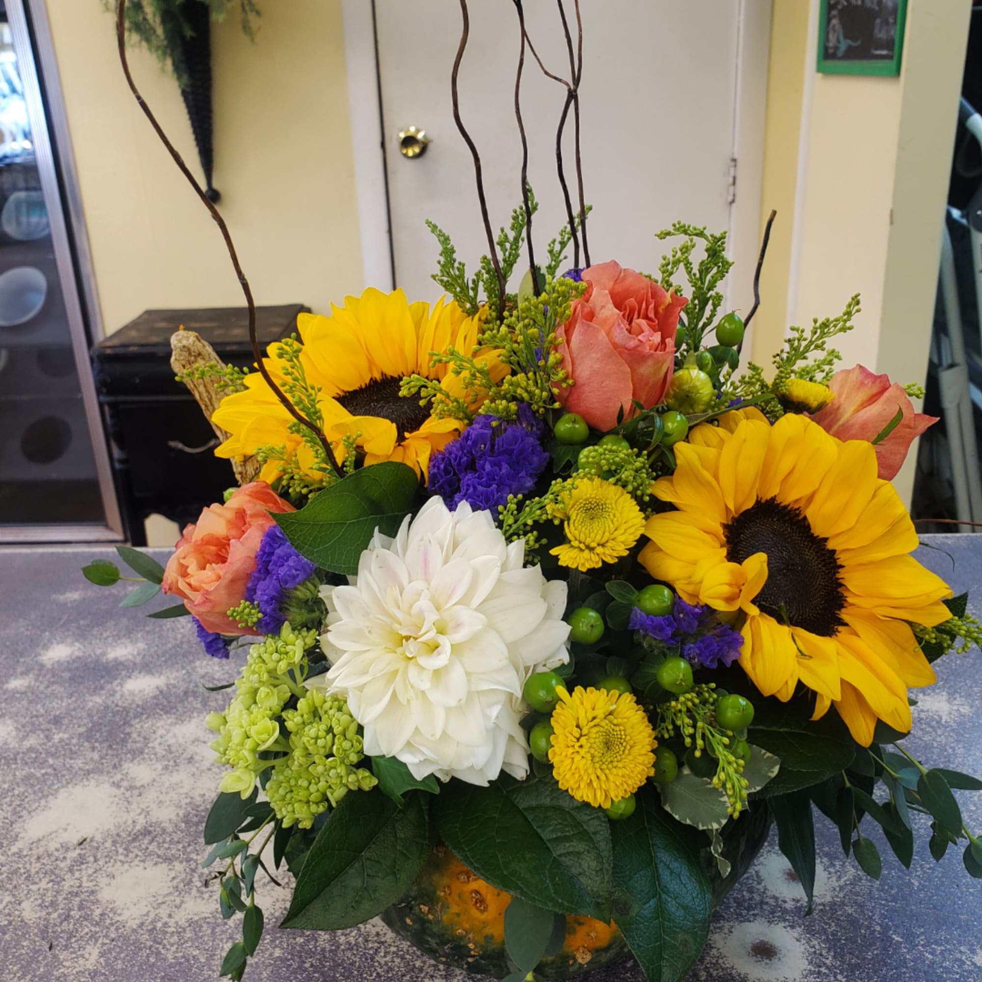 Mixed bouquet with sunflowers, roses, and a white dahlia in a vase