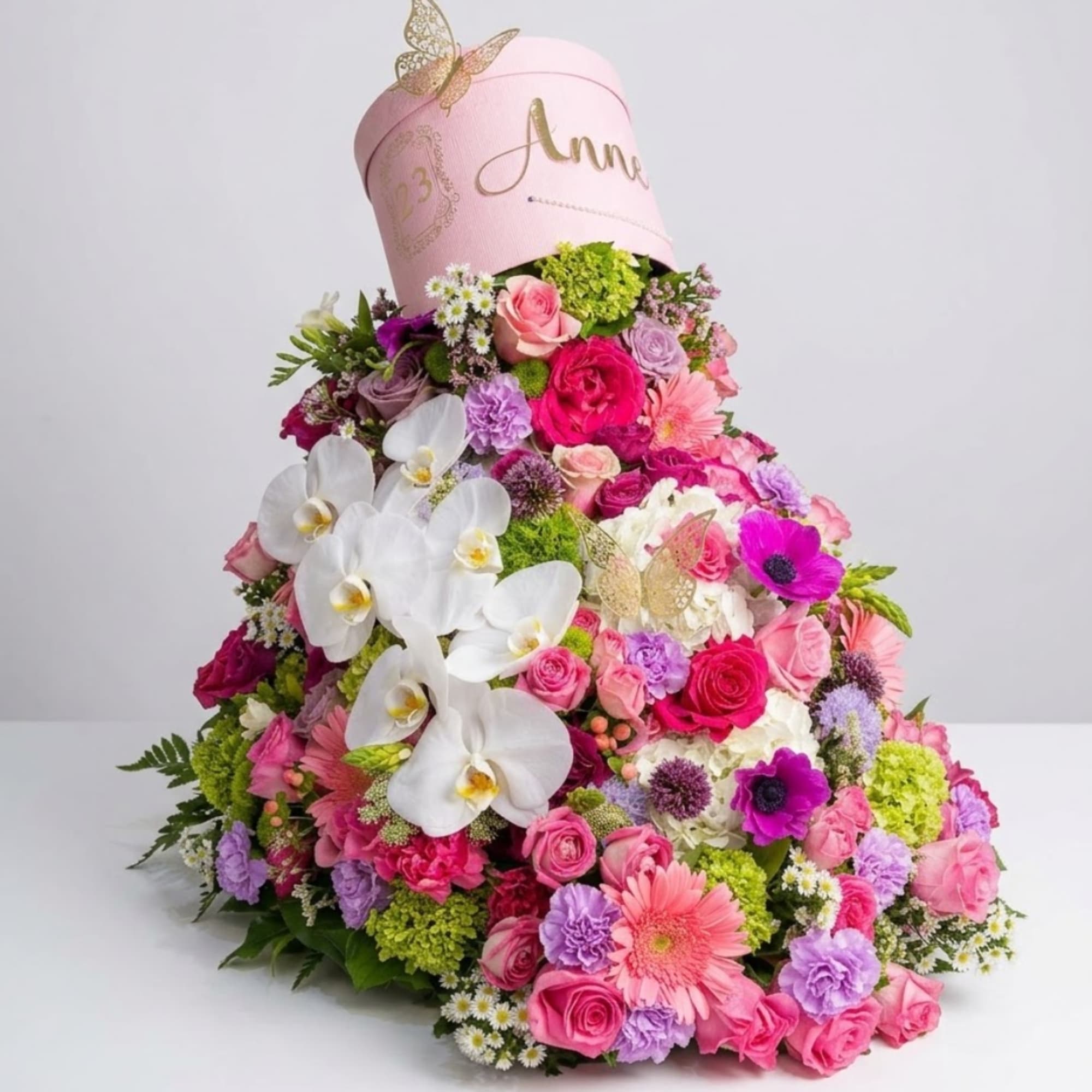 Large pink floral arrangement with white orchids and roses in a pink hatbox