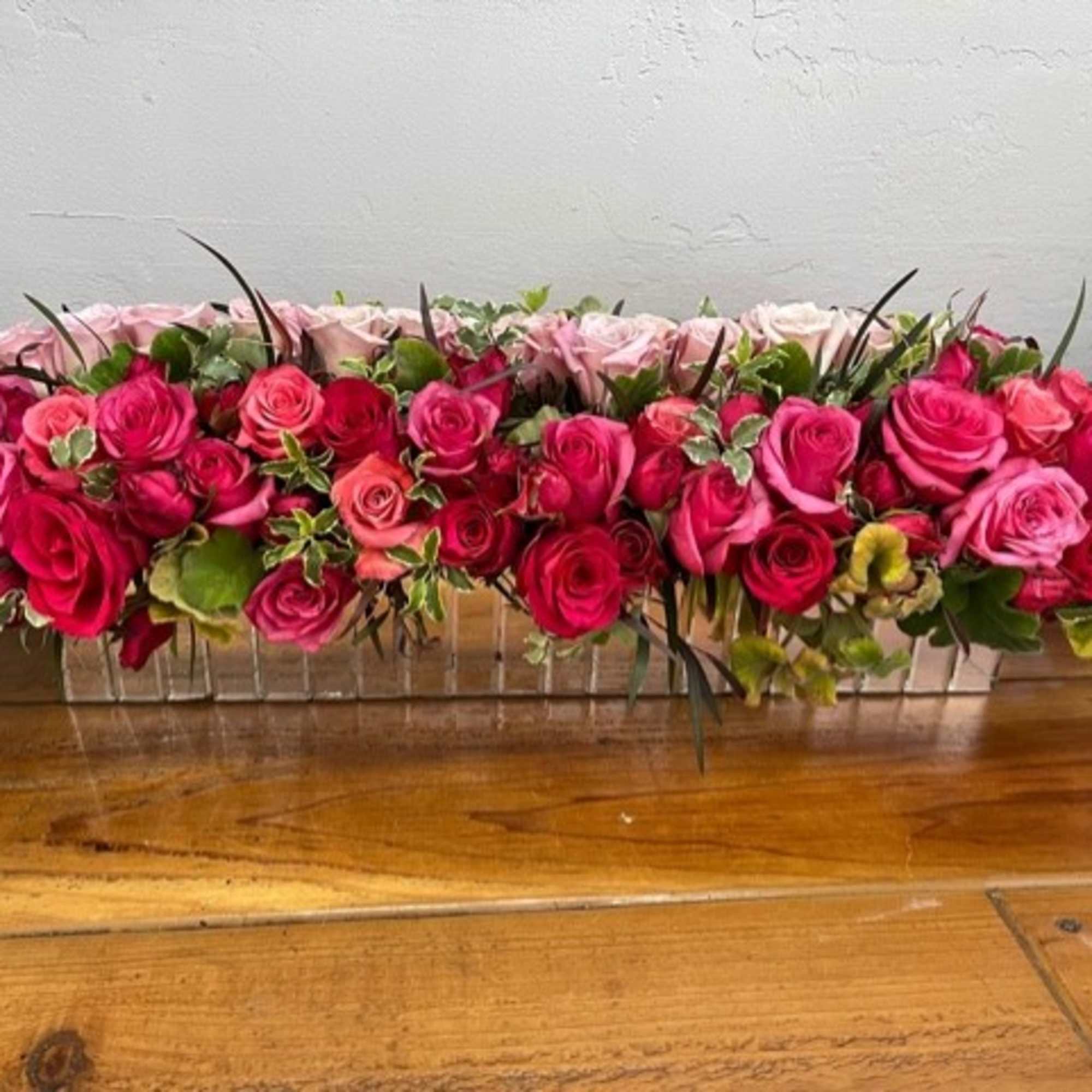 An opulent display of all pink roses arranged in a keepsake mirrored
