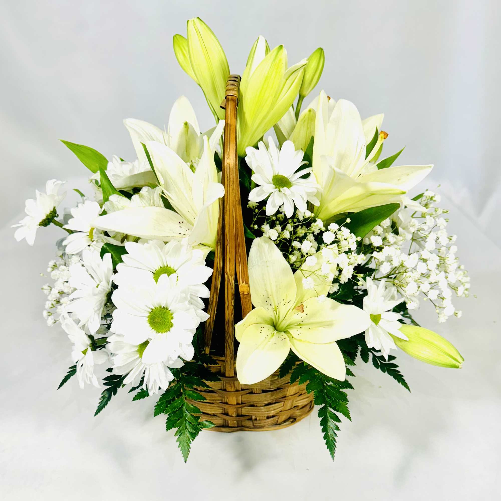 White lilies and daisies arranged in a wicker basket