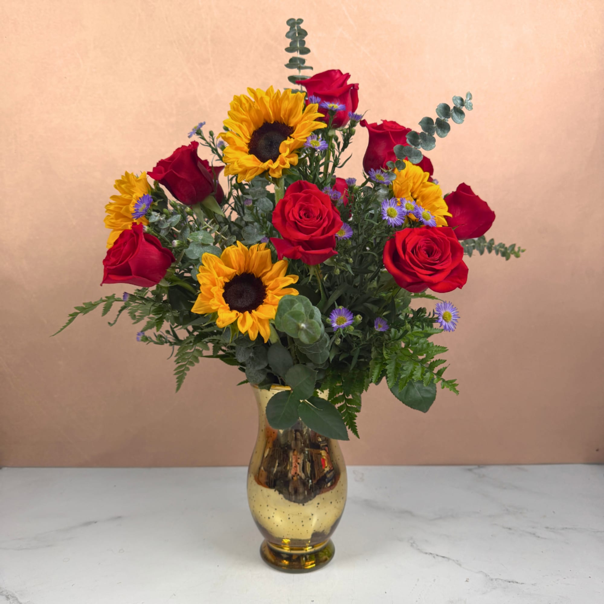 Red roses and sunflowers arranged in a gold vase