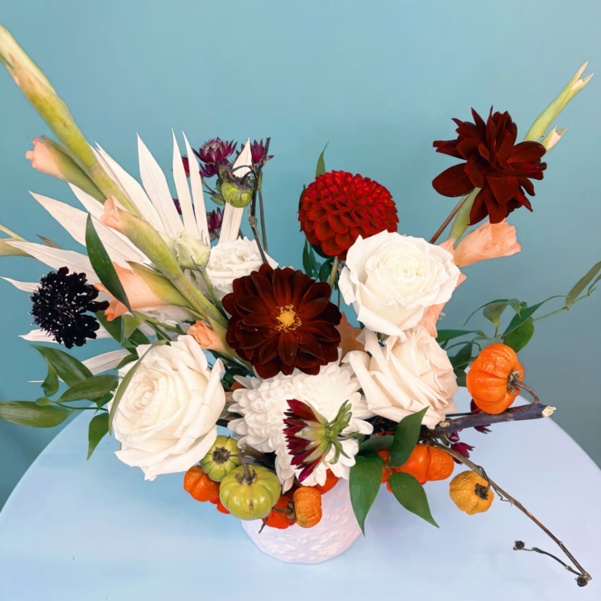 Mixed floral arrangement with white roses and dark red blooms in a white vase