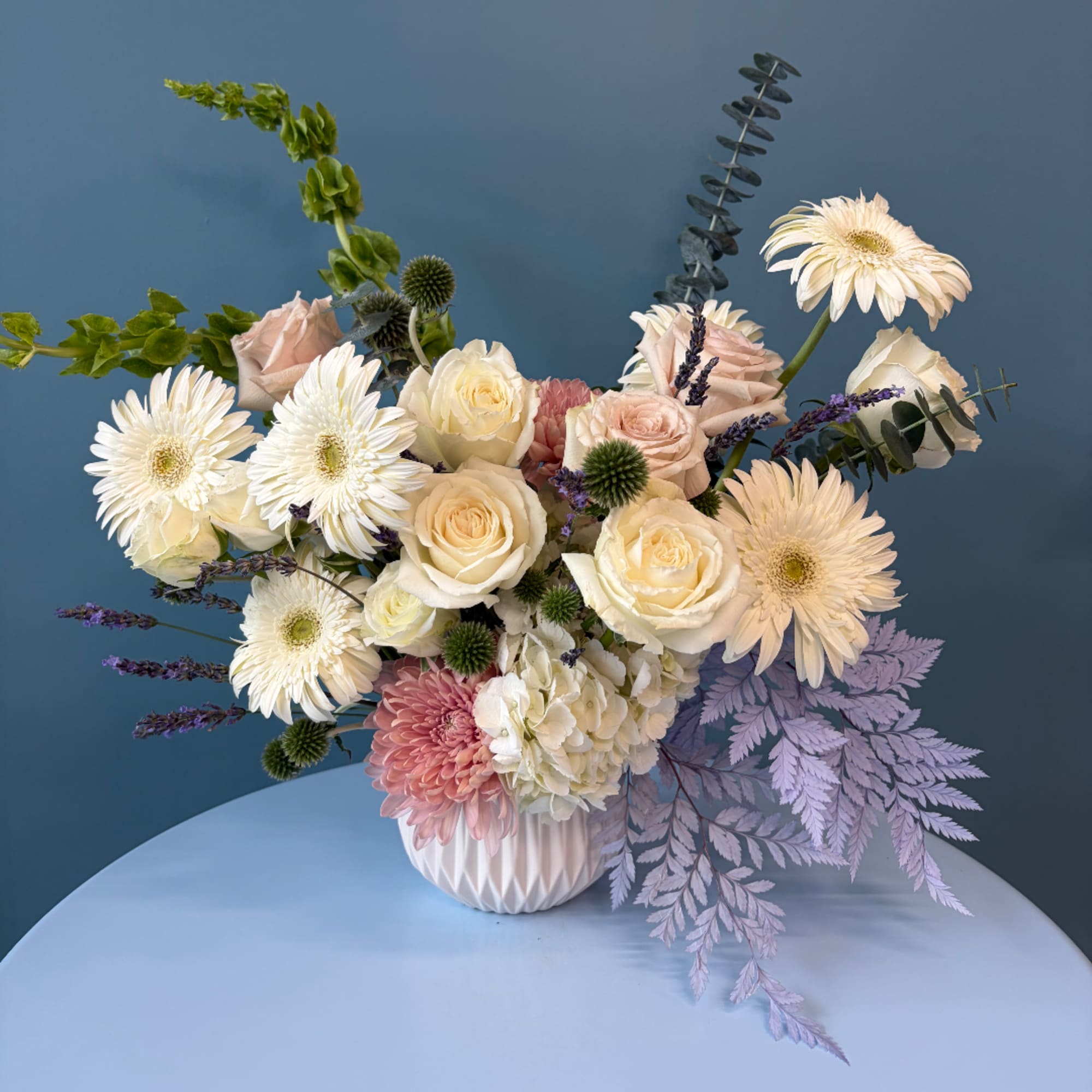 Mixed bouquet of cream and blush flowers in a white vase
