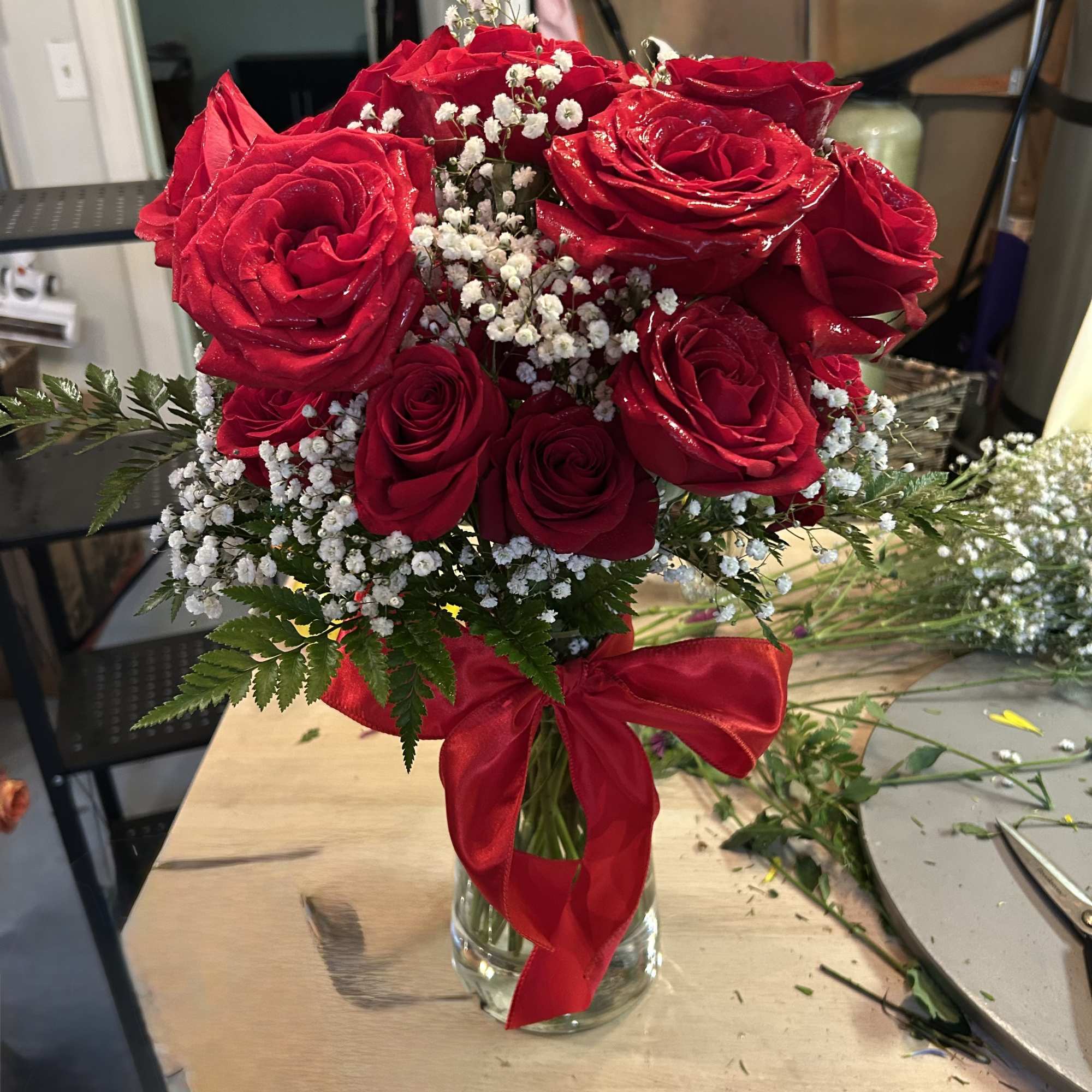Red roses arranged in a clear glass vase with a red ribbon