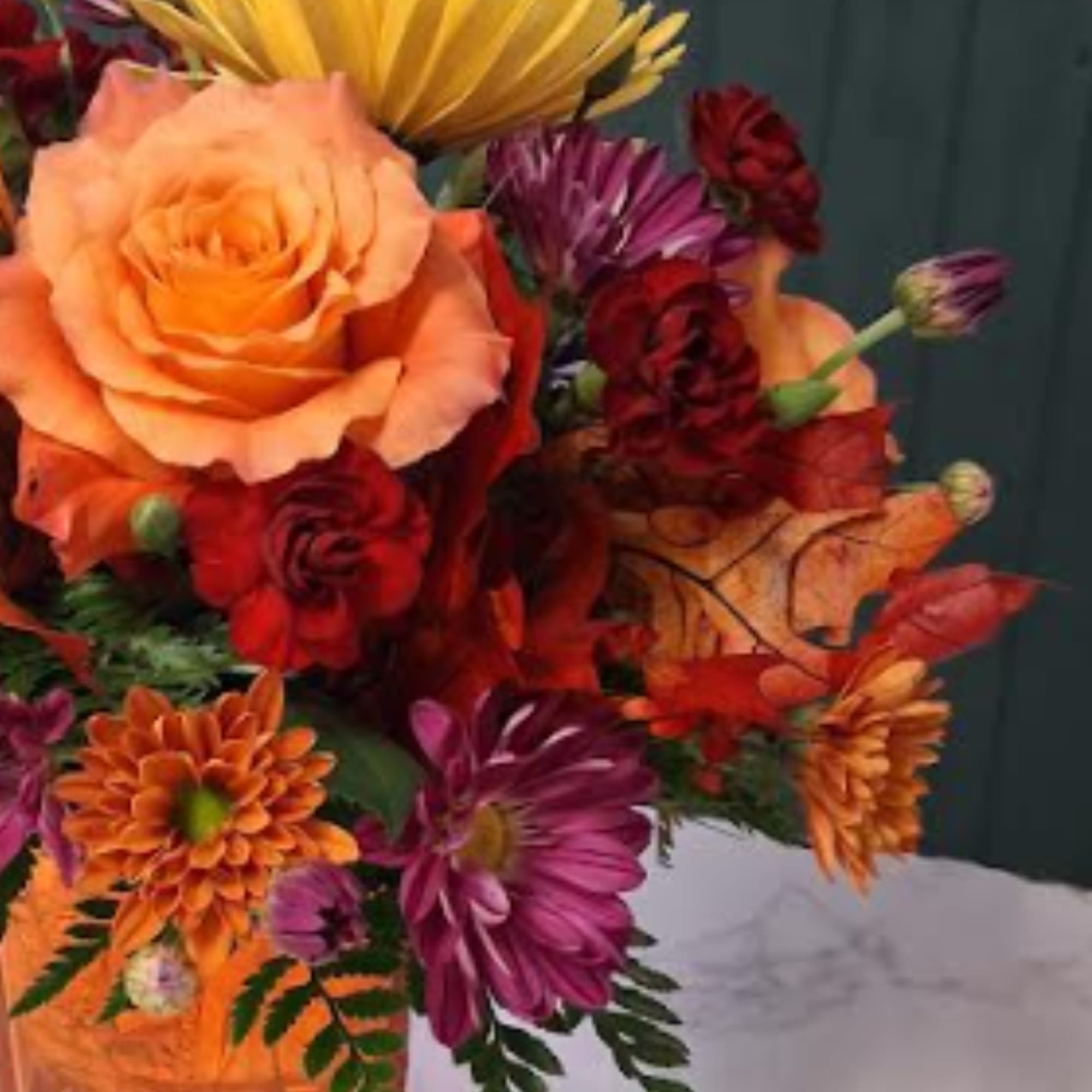 Bouquet of orange, red, and purple flowers with a large peach rose