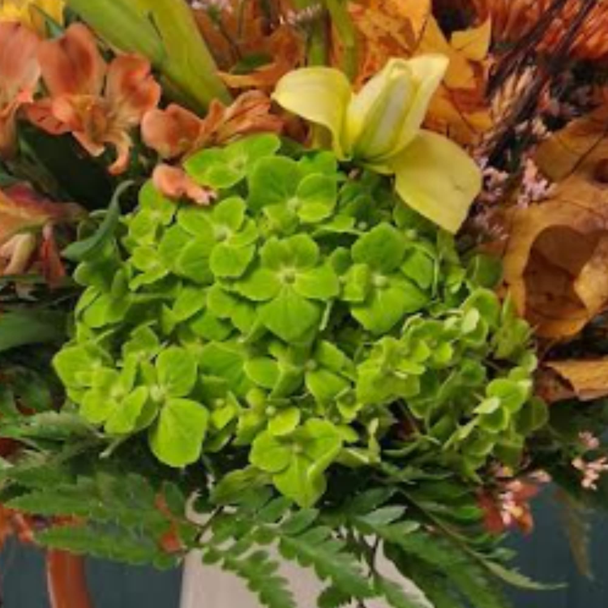 Green hydrangea bouquet with orange lilies and autumn foliage