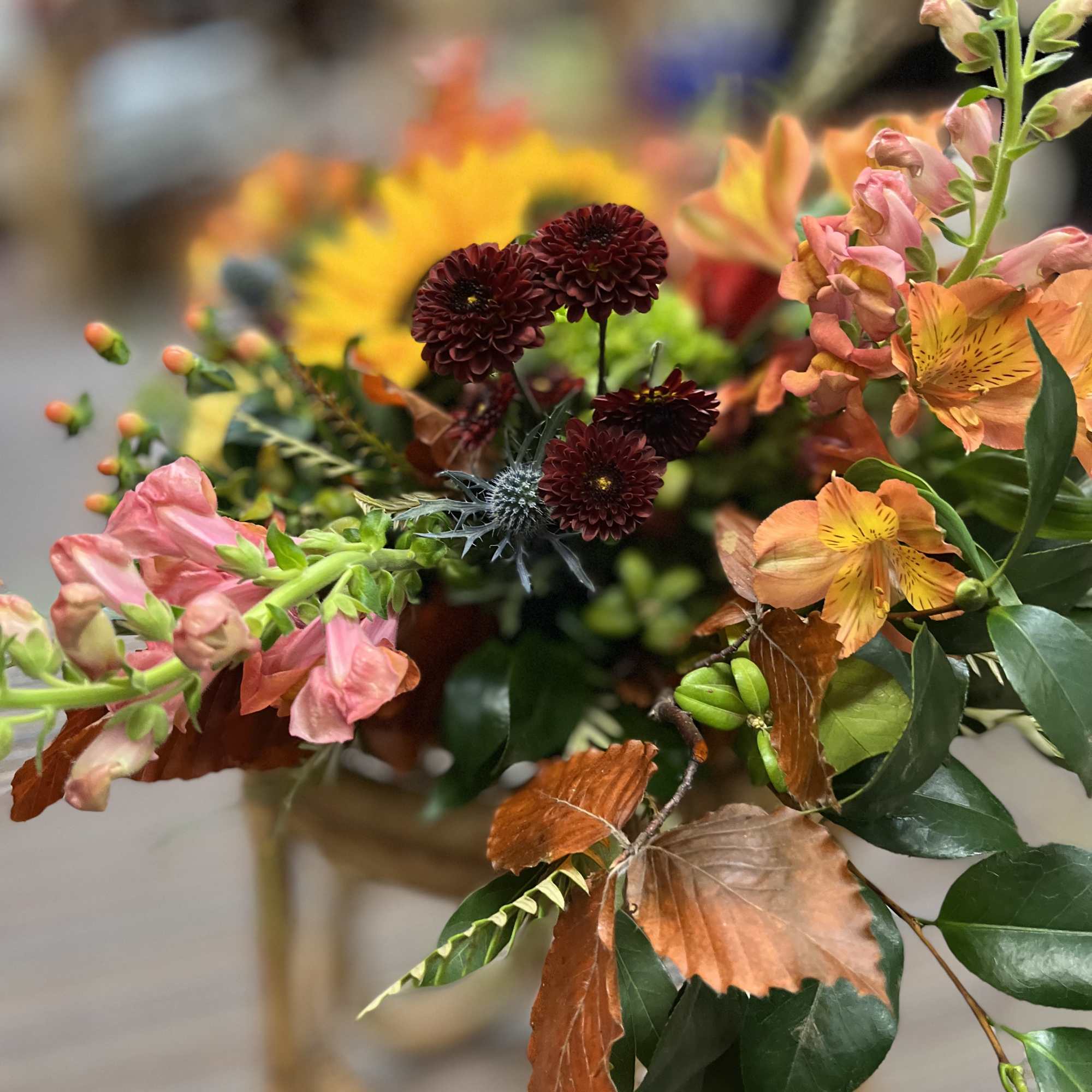 Mixed bouquet with orange, pink, and burgundy flowers in a vase