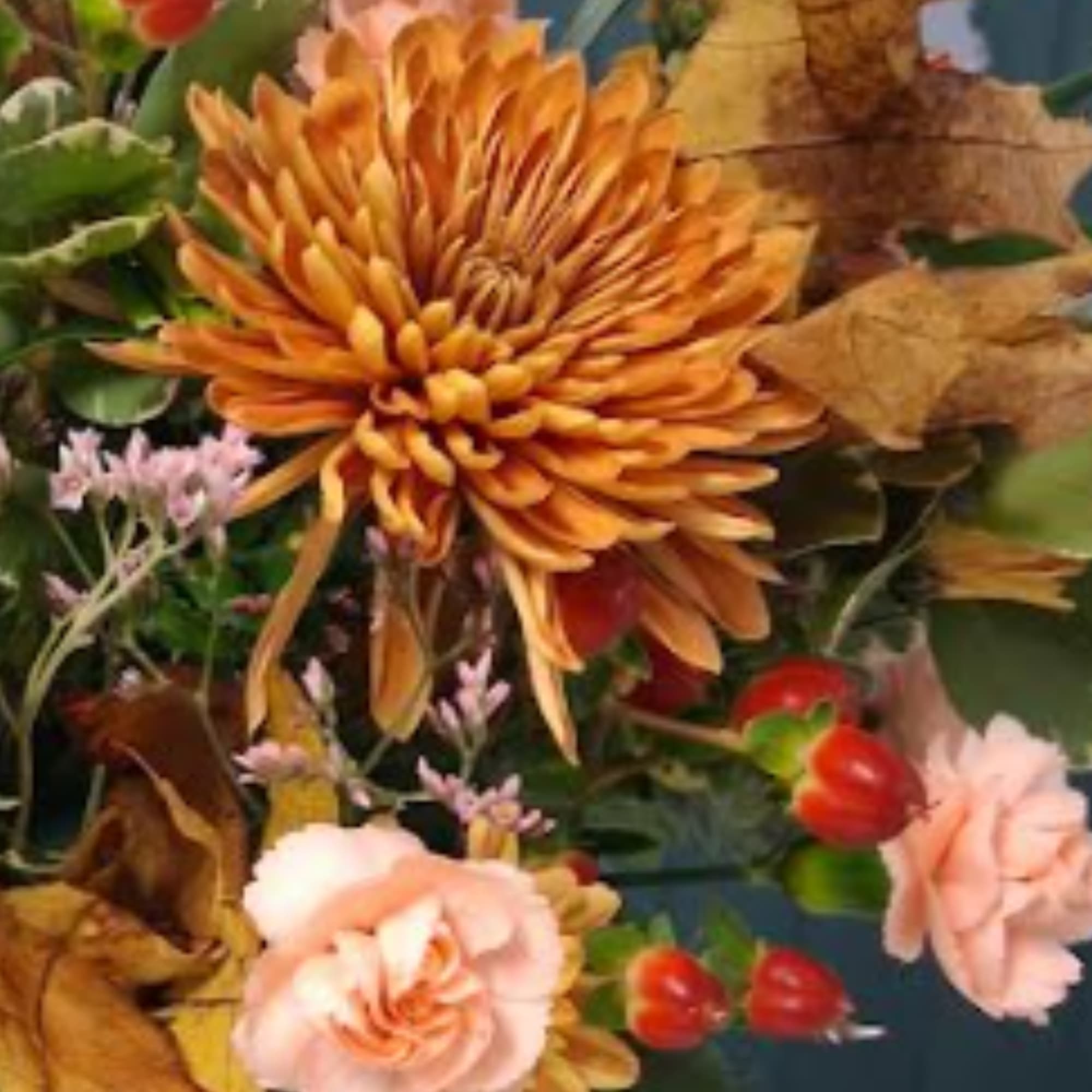 Orange chrysanthemum bouquet with pale pink roses and autumn leaves