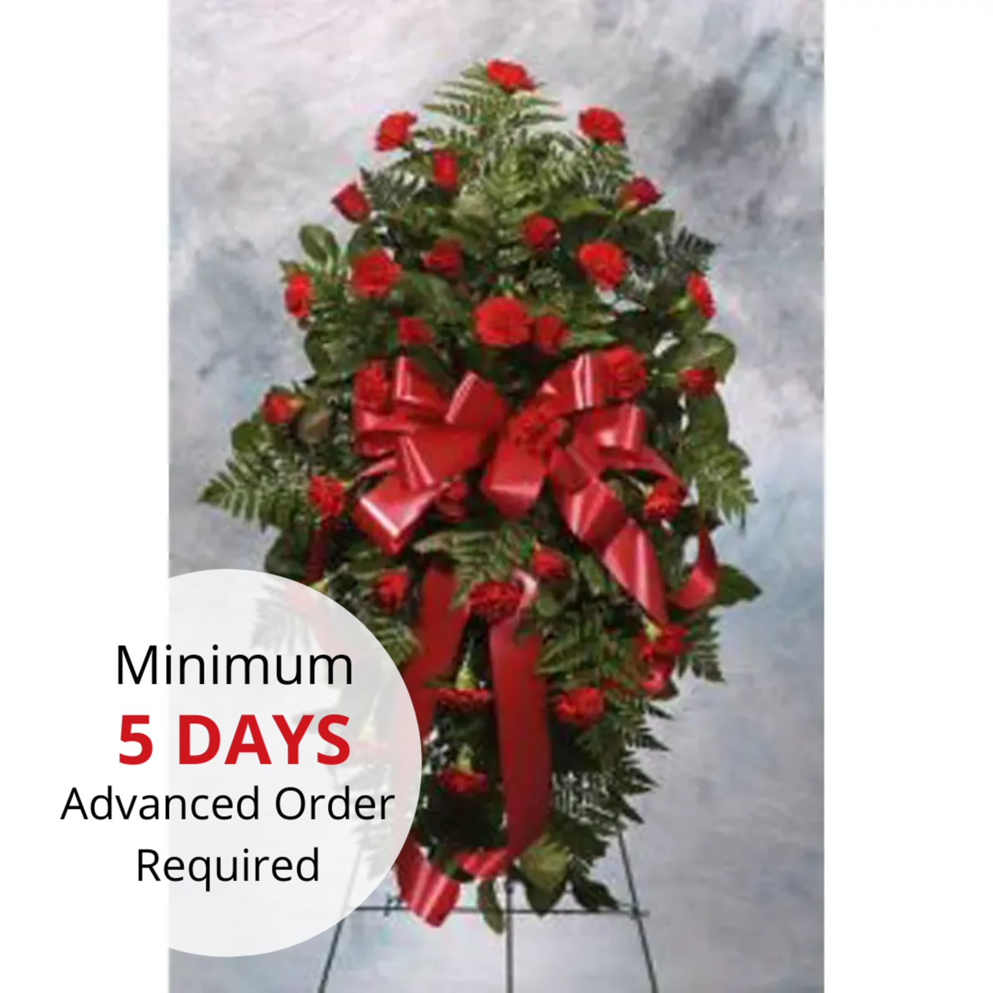Tall standing spray of red carnations with a large red bow on an easel.