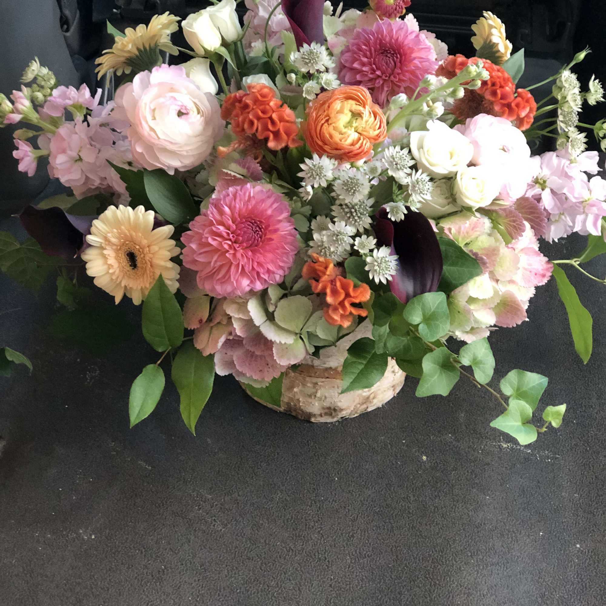 Mixed bouquet of pink, white, orange, and purple flowers in a low container
