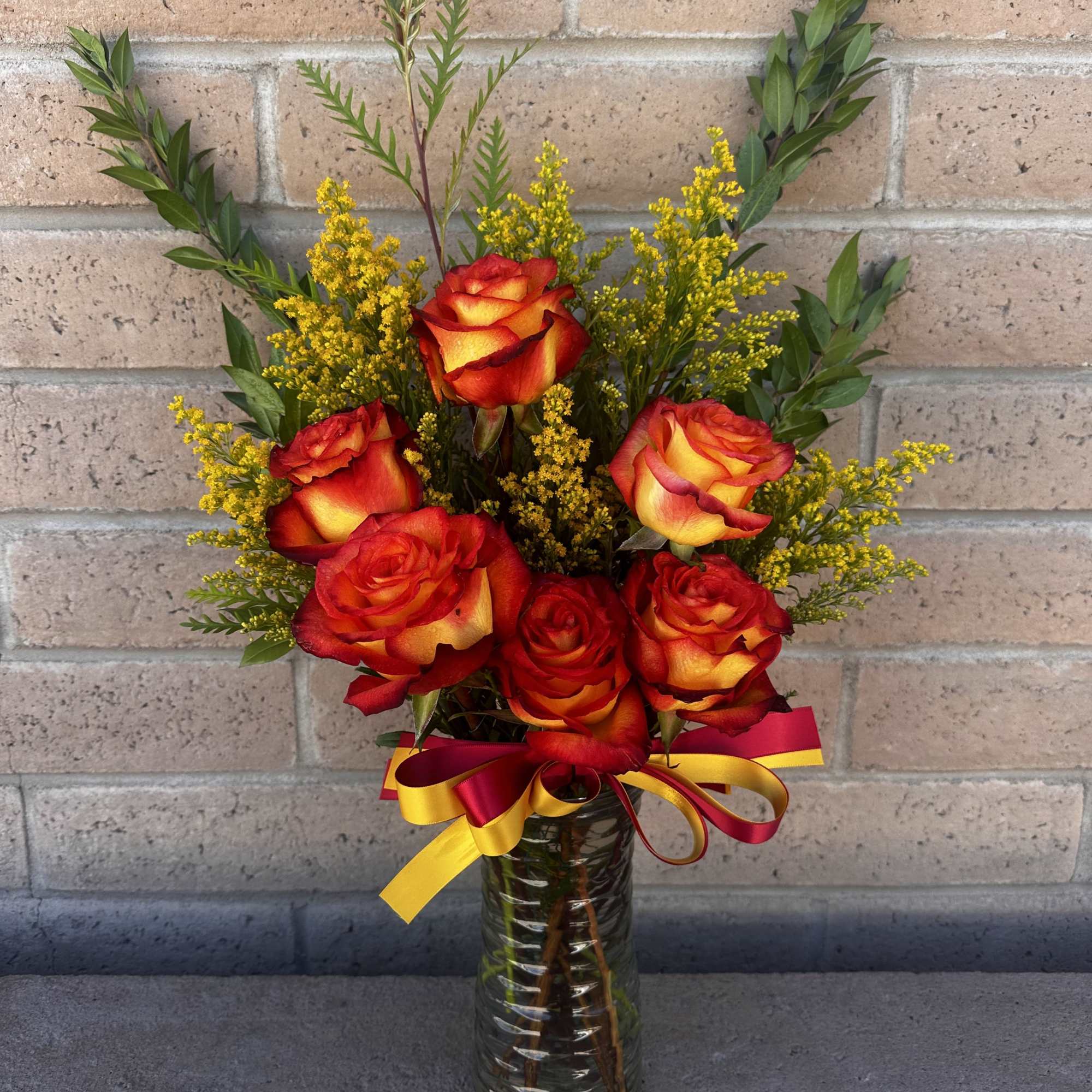 Bouquet of red and yellow roses in a glass vase with a ribbon
