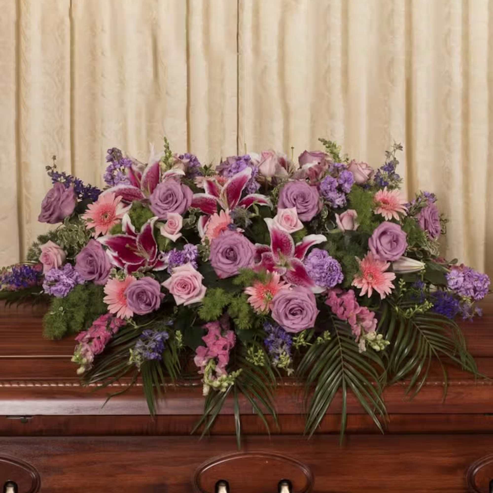 Large purple and pink floral spray on a casket