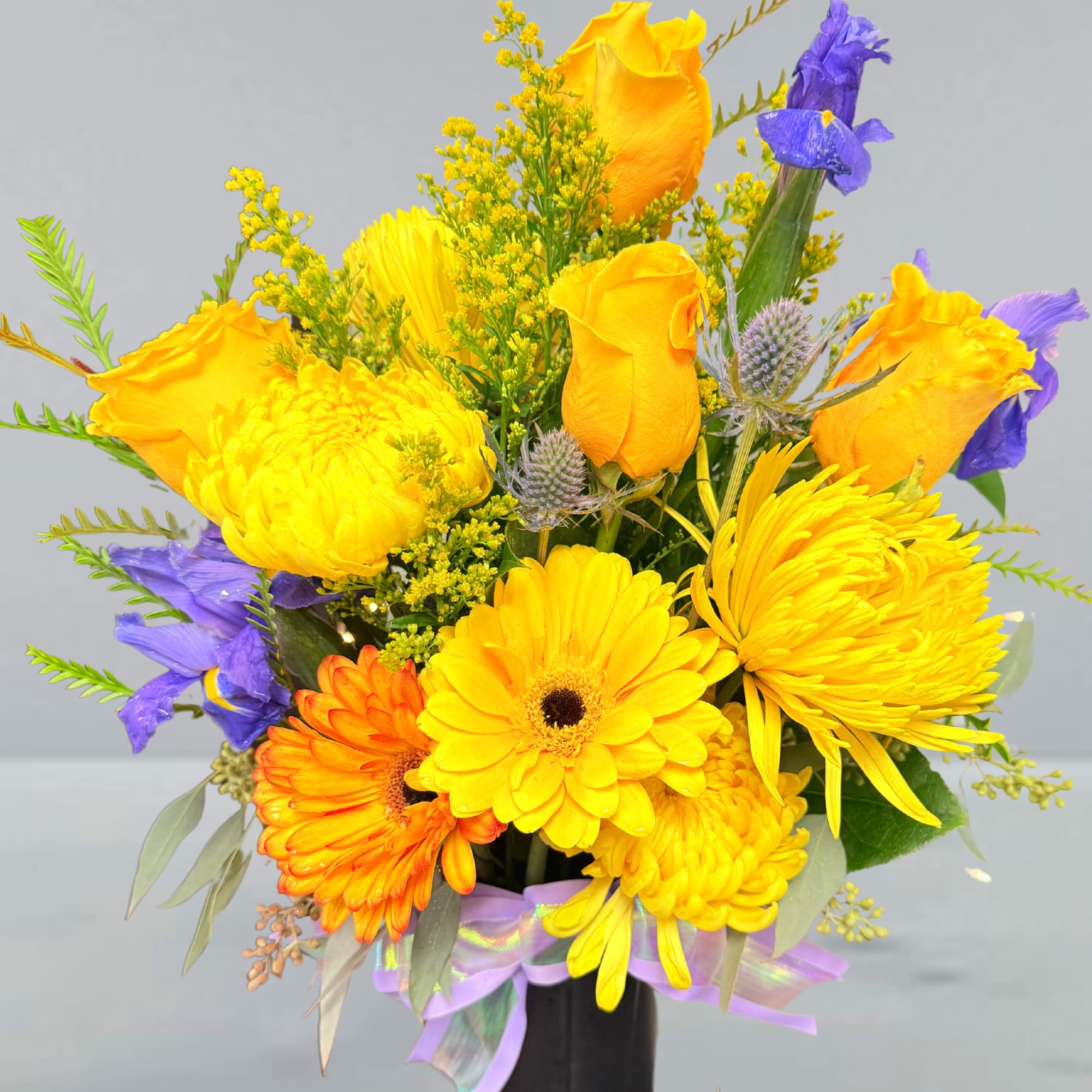 Bright yellow and purple mixed bouquet in a black vase