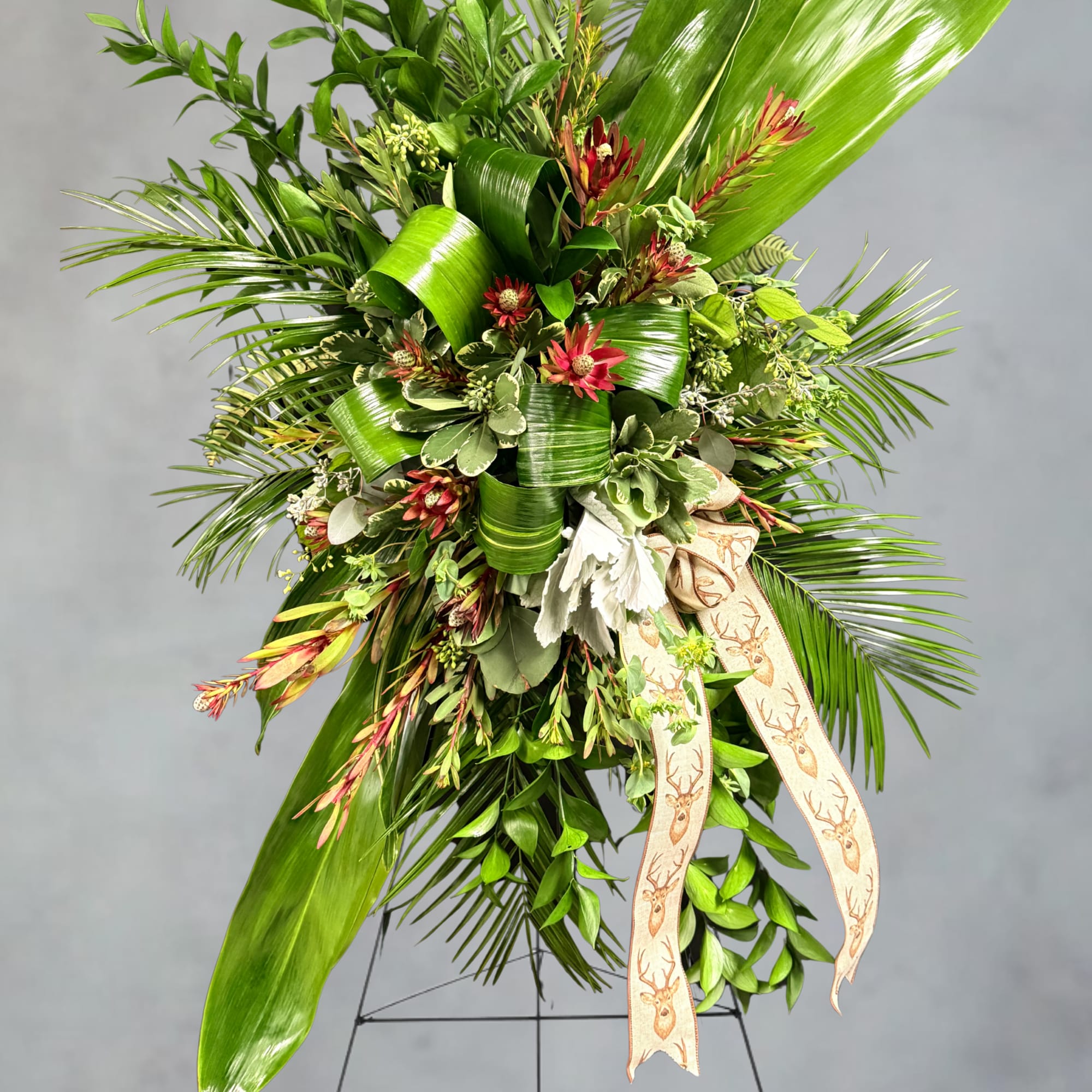 Large green floral spray with red accents and a deer-print ribbon