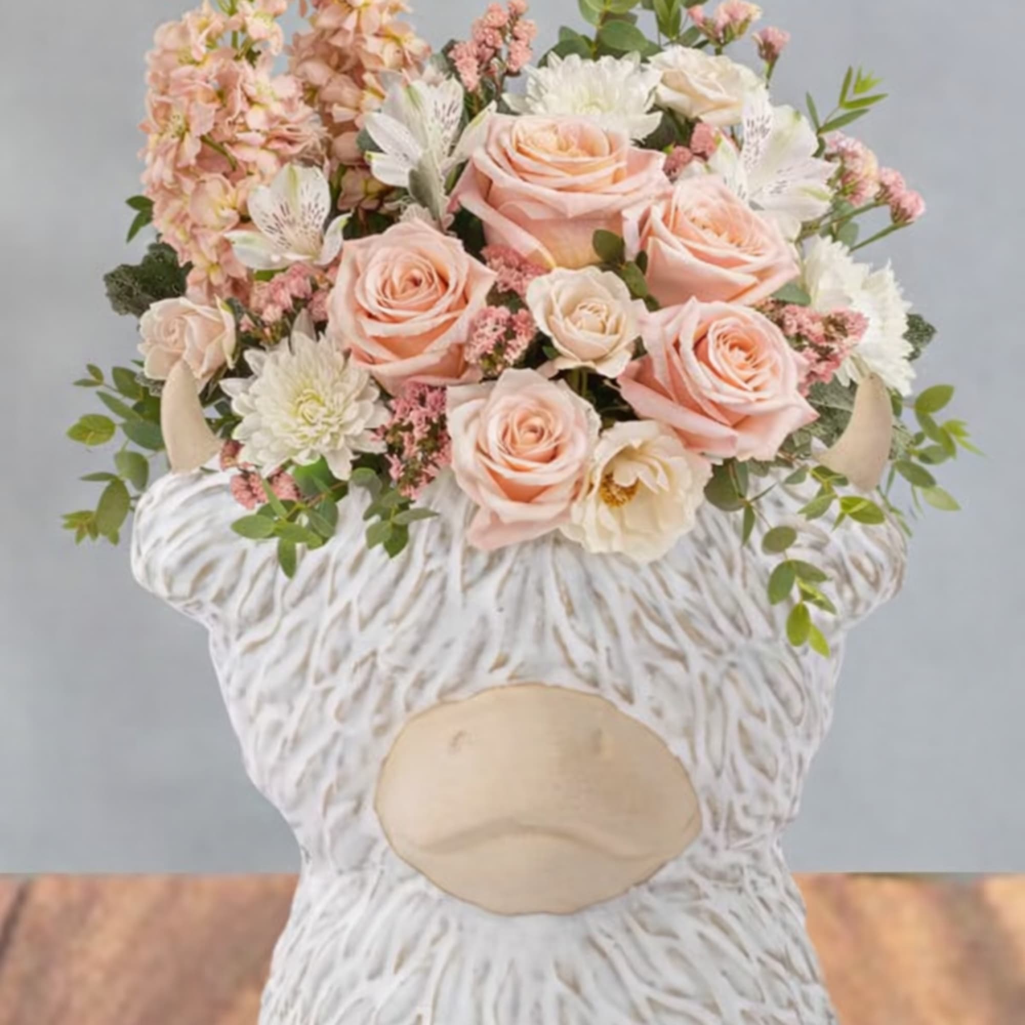Soft peach roses and blush blooms gathered in a compact, rounded bouquet