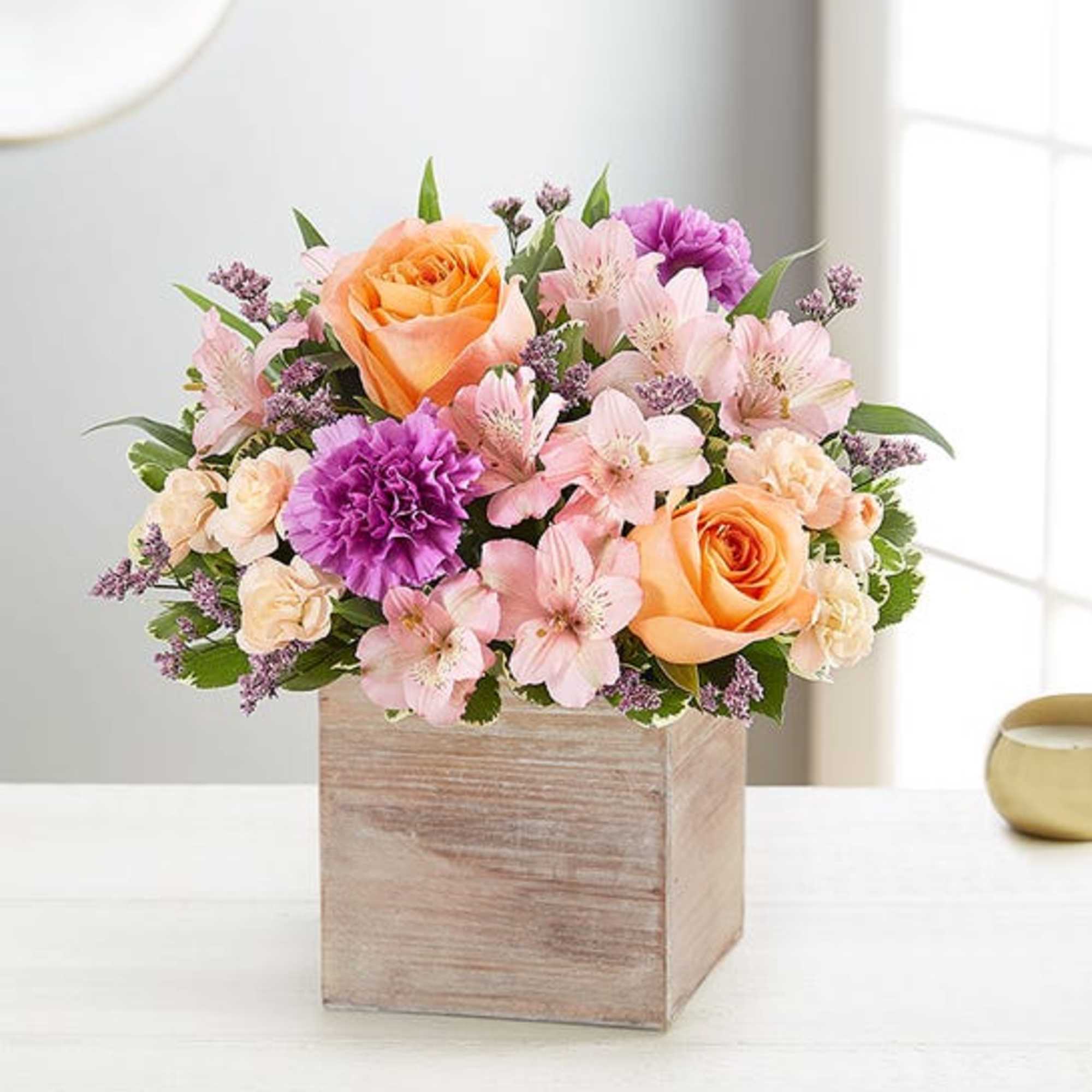 Arrangement of peach roses and pink flowers in a wooden box