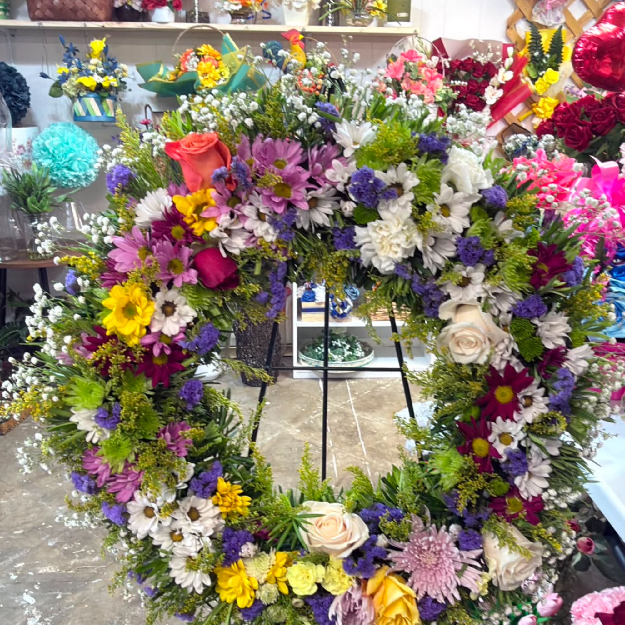 Large floral wreath with mixed daisies, roses, and purple accents