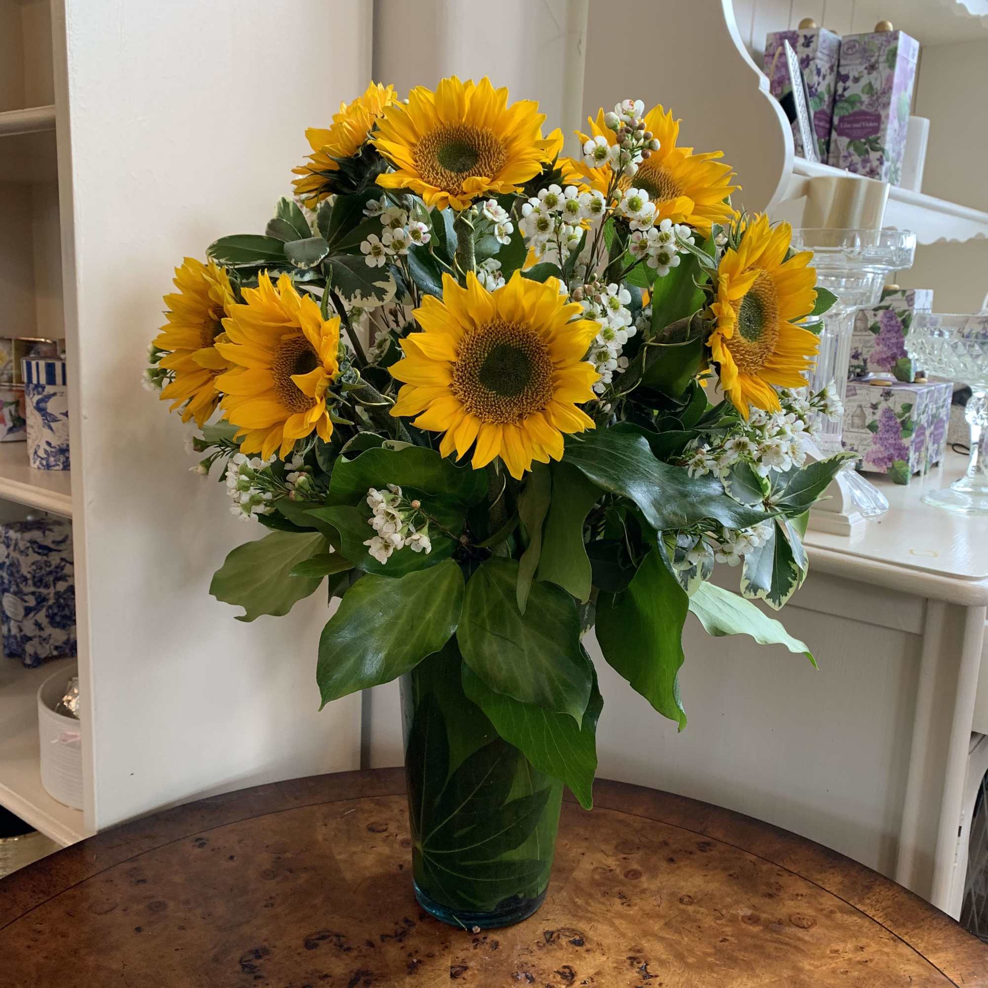 Sunflowers and small white flowers arranged in a tall glass vase