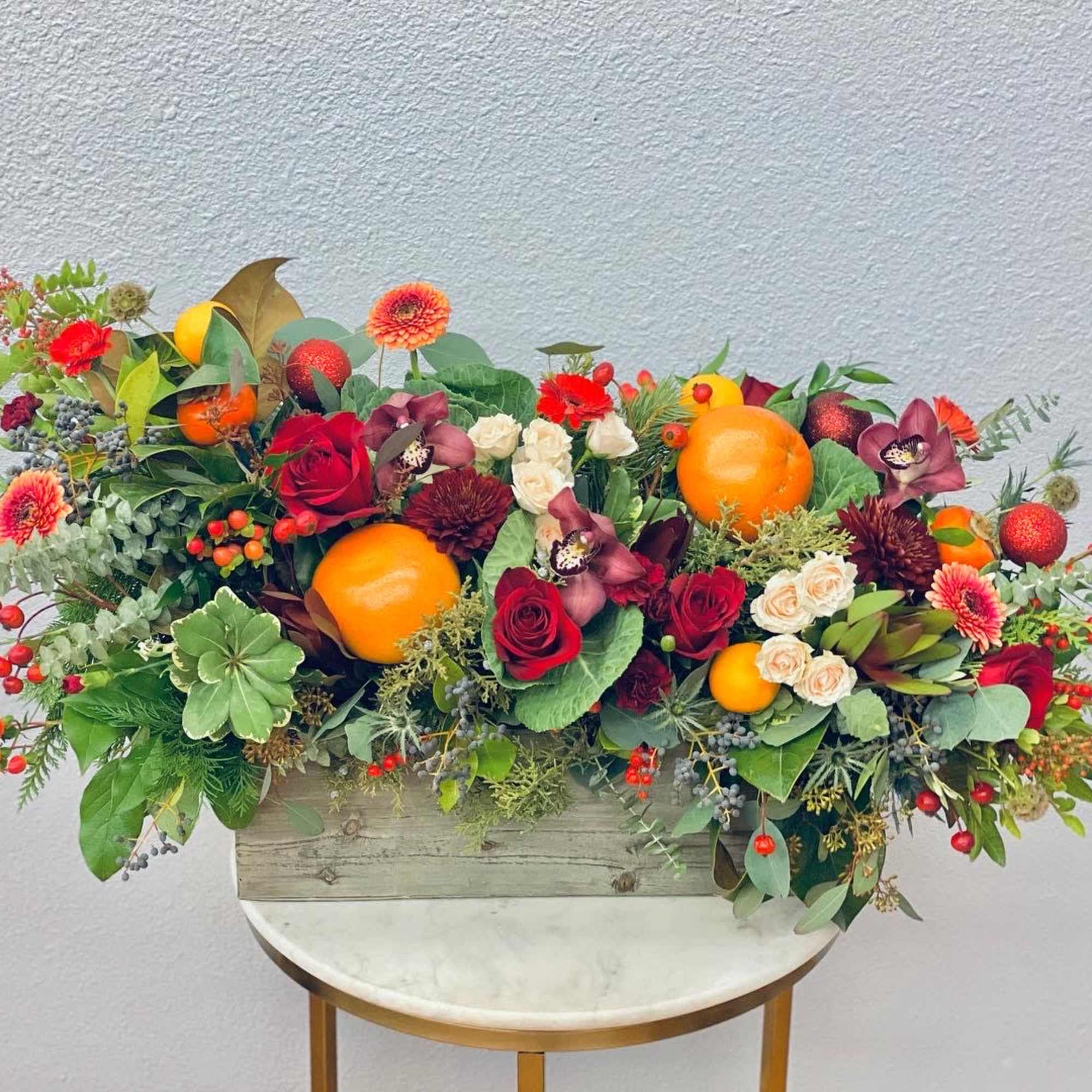 Mixed floral arrangement with oranges in a wooden box