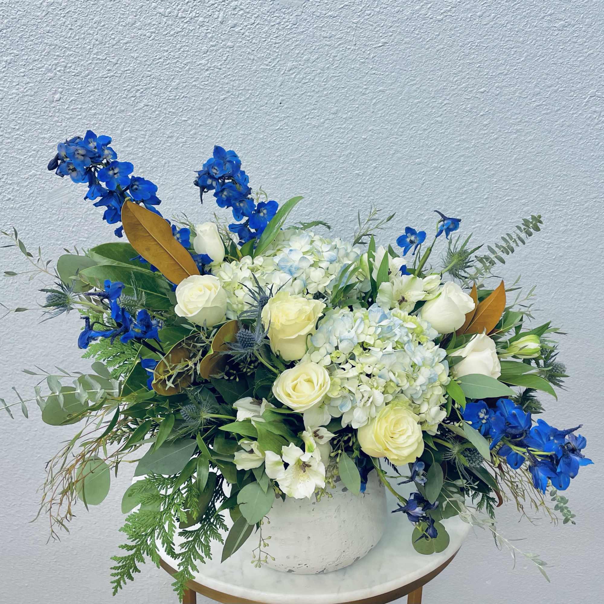 White roses and hydrangeas with bright blue flowers in a white vase
