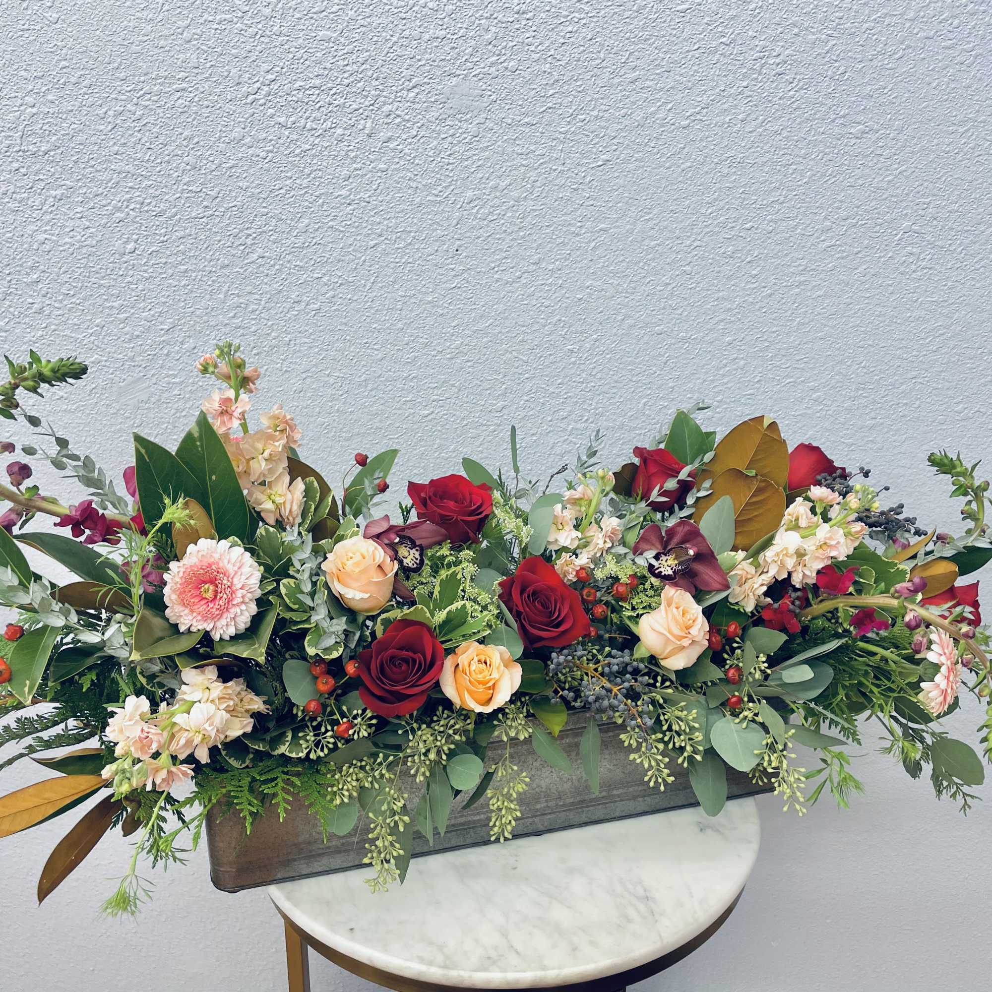 Long floral centerpiece with red and peach roses in a rectangular container