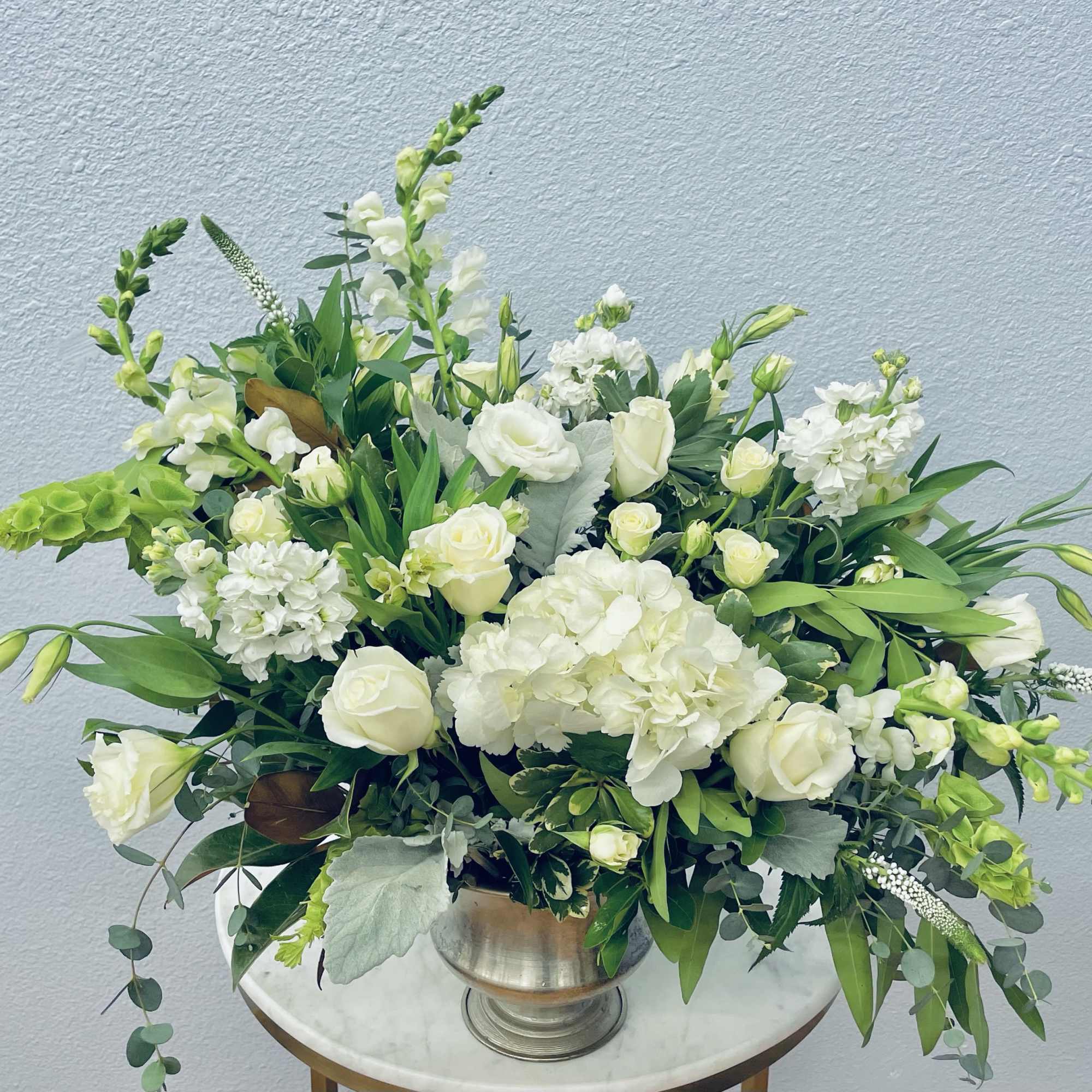 White roses and hydrangeas arranged in a silver vase